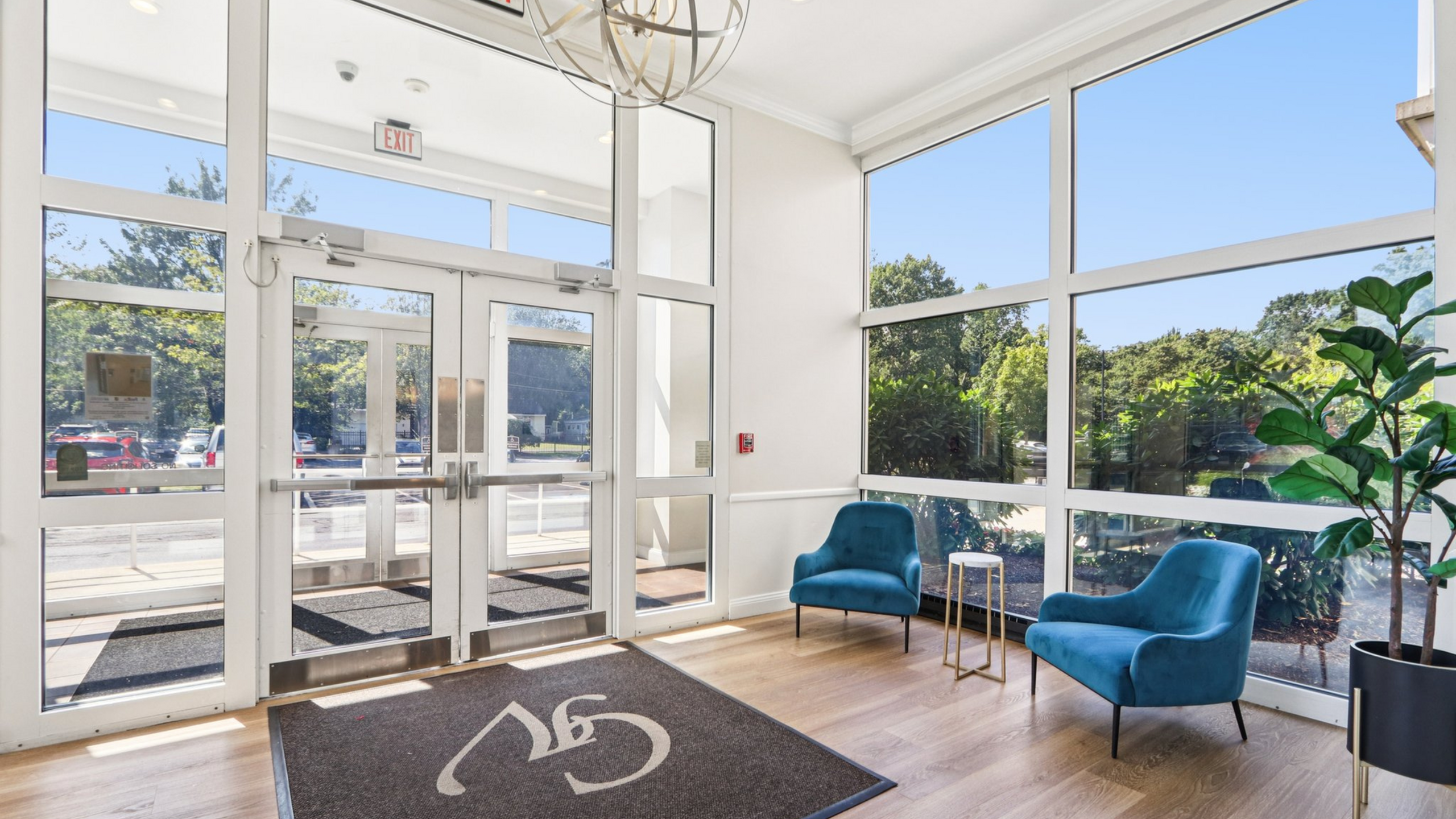 Bright and inviting lobby with modern blue chairs, large windows, and stylish decor, offering a welcoming atmosphere.