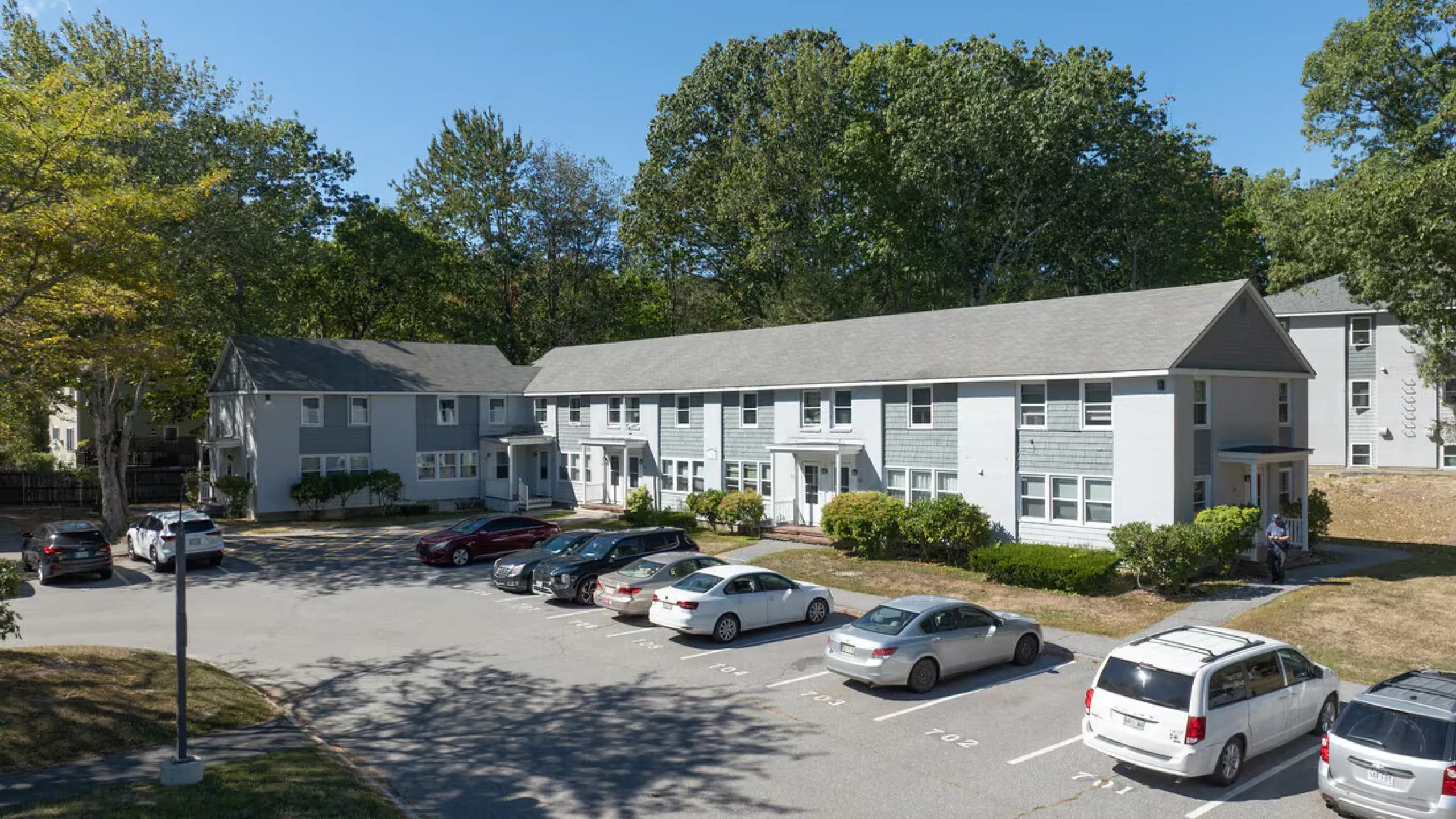 Charming apartment complex with classic architecture, surrounded by lush greenery and ample parking.