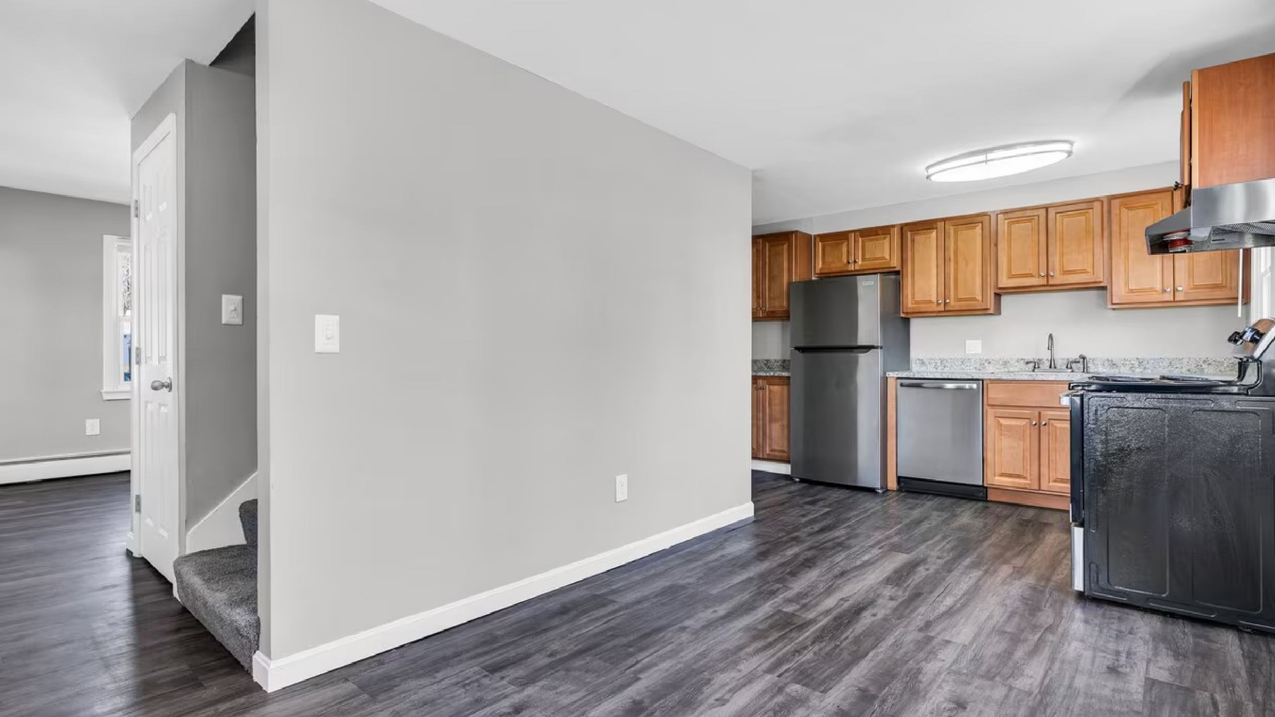 Elegant apartment interior showcasing a modern kitchen with wooden cabinetry, stainless steel appliances, and sleek dark flooring.