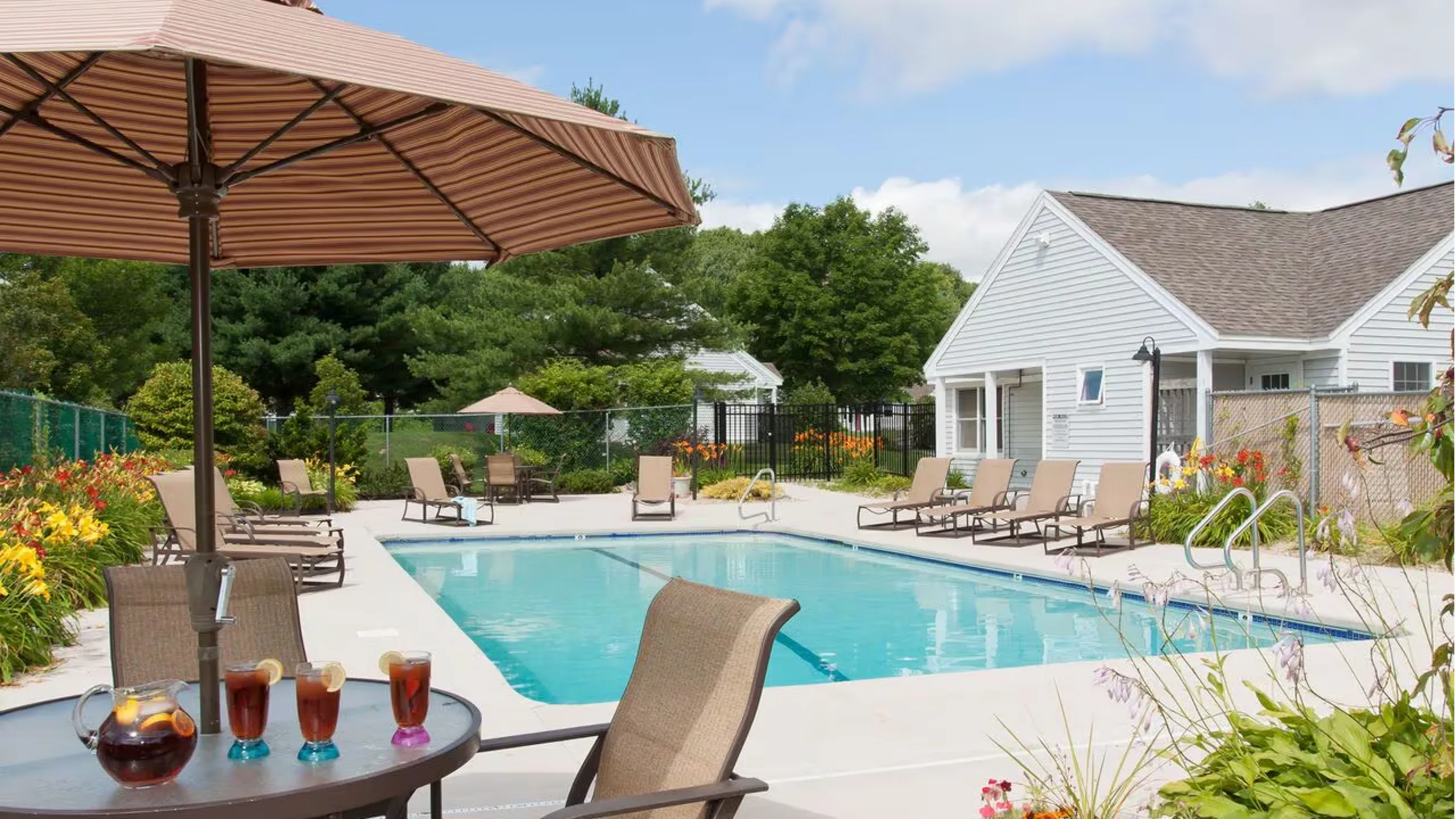 Charming outdoor swimming pool with inviting lounge chairs, vibrant flora, and refreshing drinks on a sunny day, perfect for relaxation.