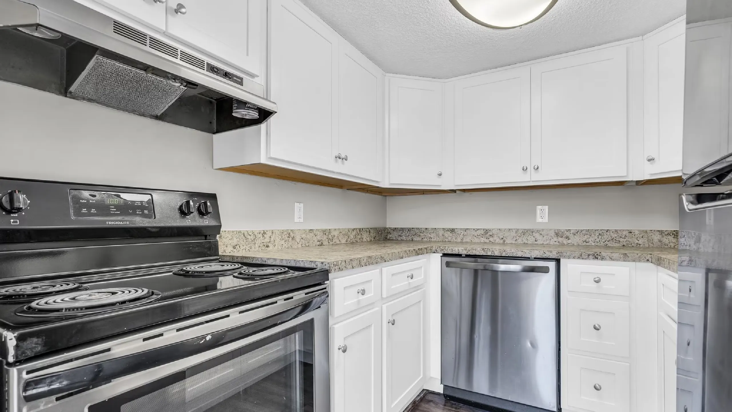 Modern kitchen with sleek stainless steel appliances, elegant granite countertops, and chic white cabinetry.