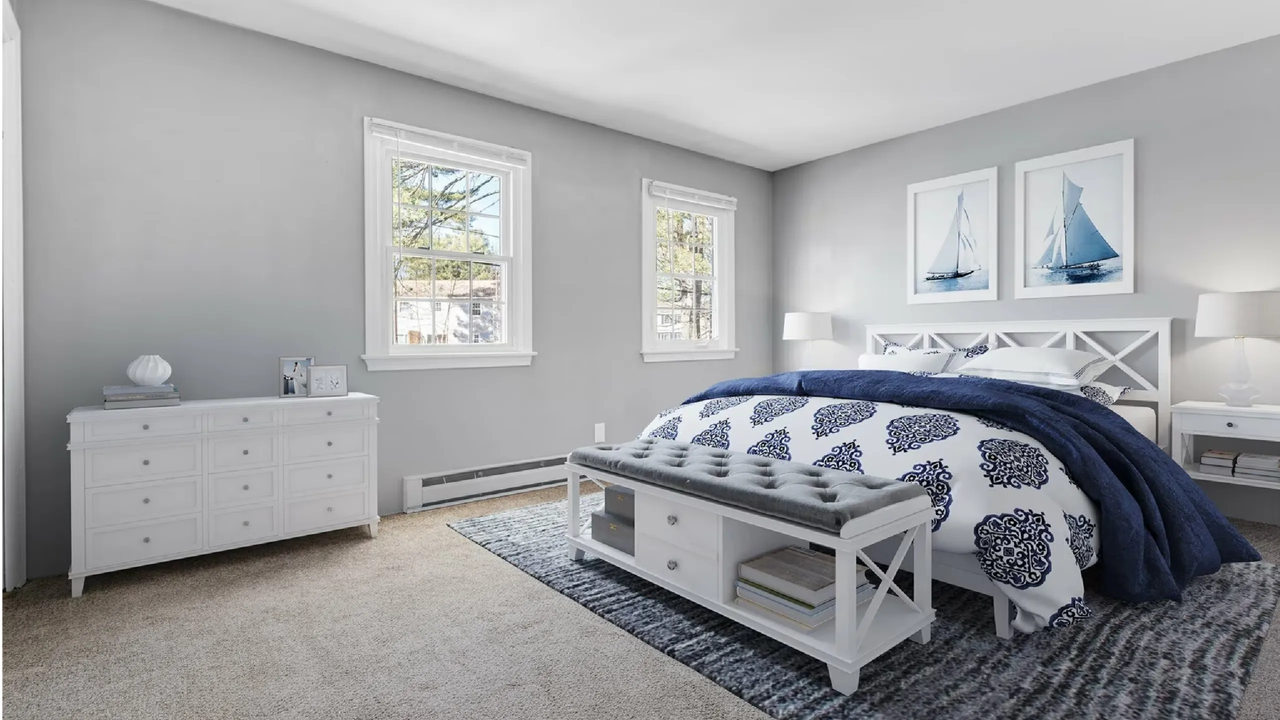 Bright and elegant bedroom featuring nautical-themed decor, plush bedding, and large sunlit windows.