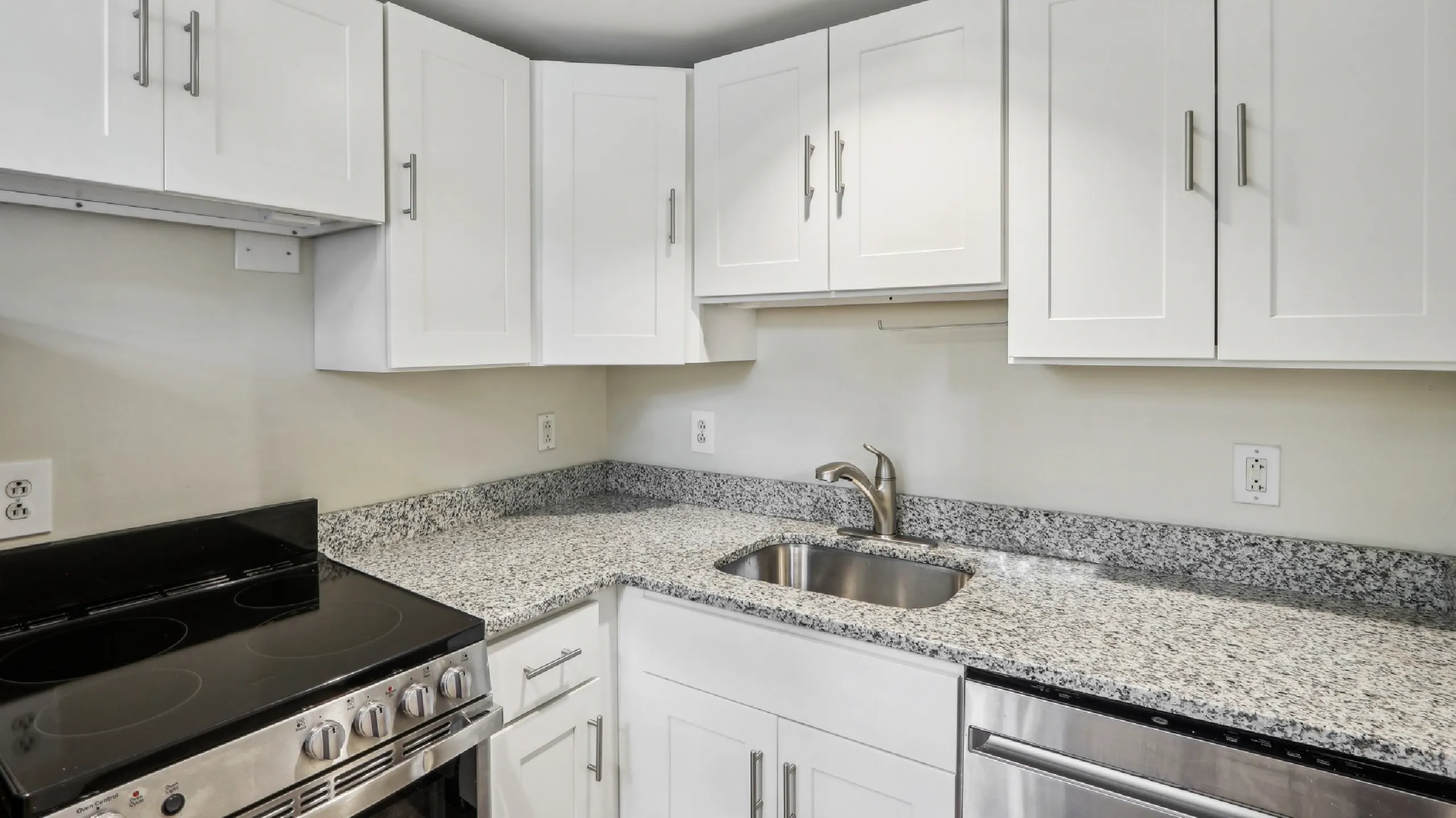 Modern kitchen with sleek white cabinetry, granite countertops, and stainless steel appliances.