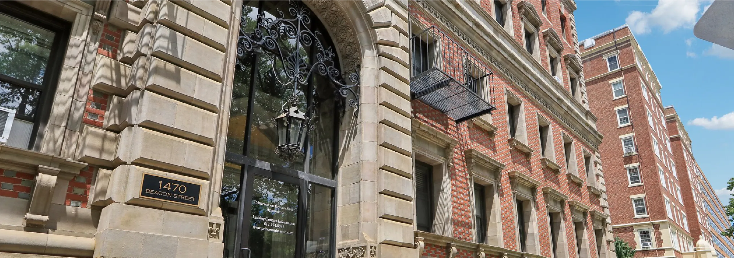 Elegant entrance of historic apartment building with ornate lantern and classic brick facade at 1470 Beacon Street.