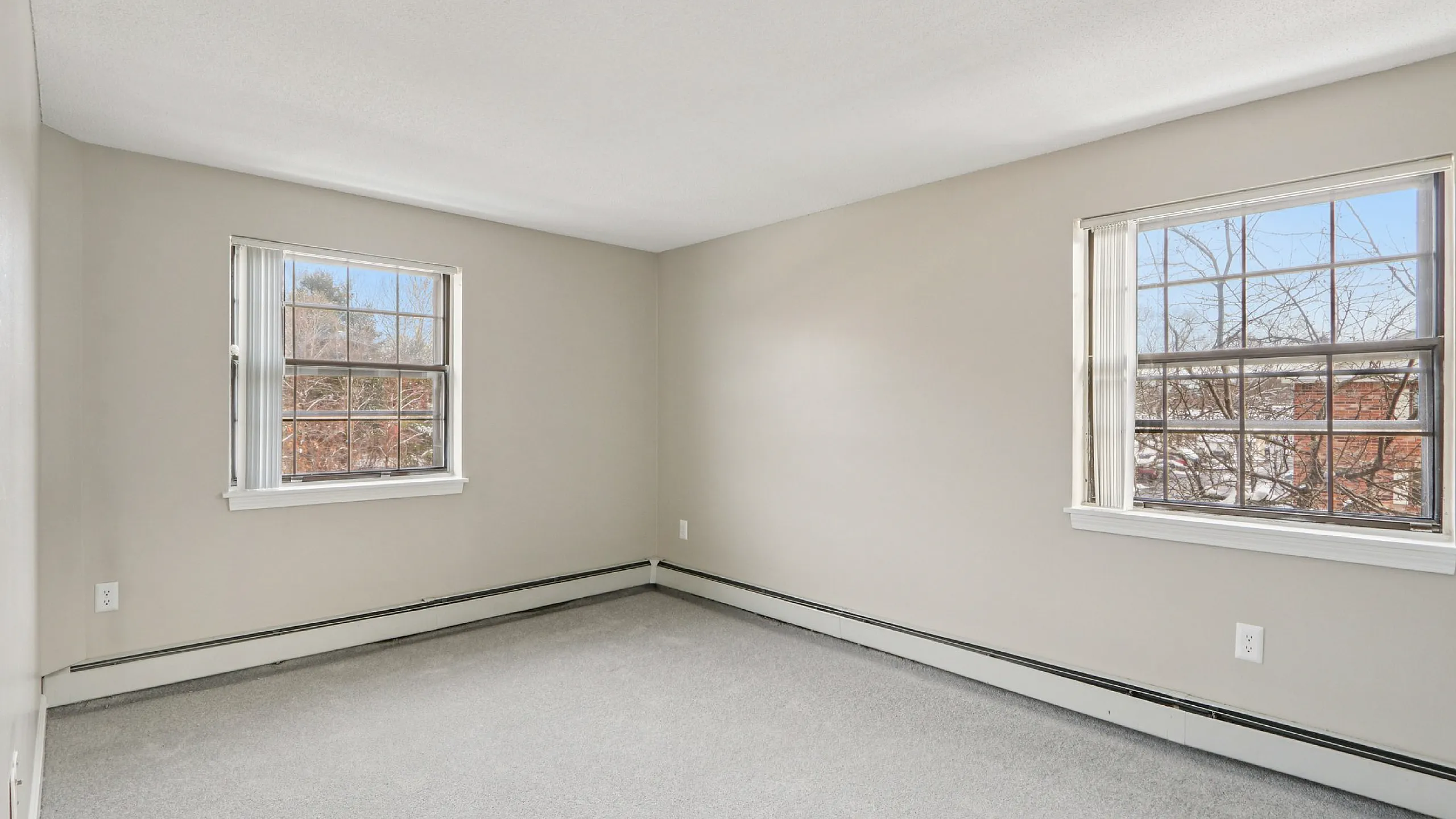 Bright and airy apartment bedroom featuring large windows and soft carpeting.
