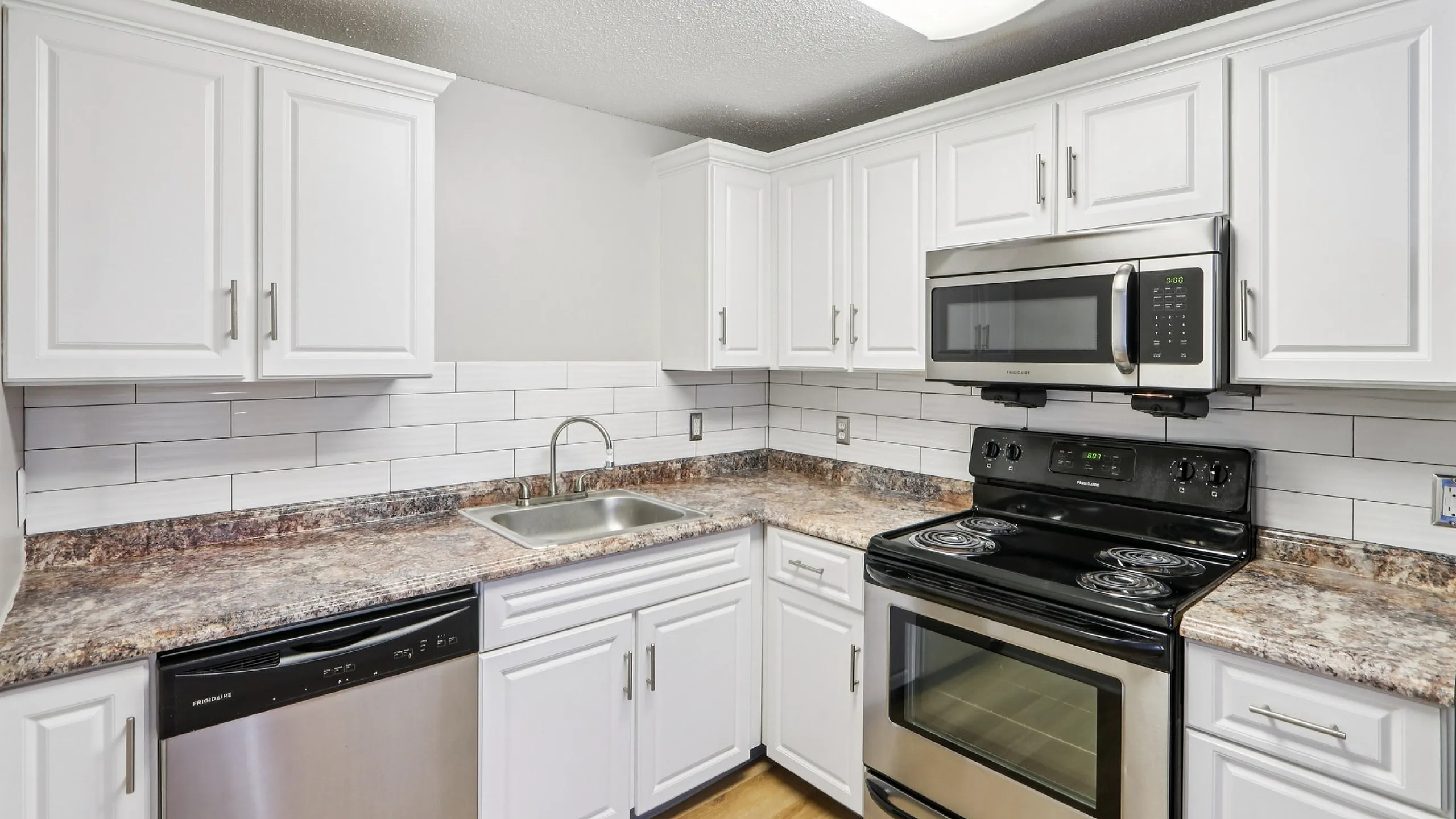 Modern kitchen with sleek white cabinets, granite countertops, and stainless steel appliances.