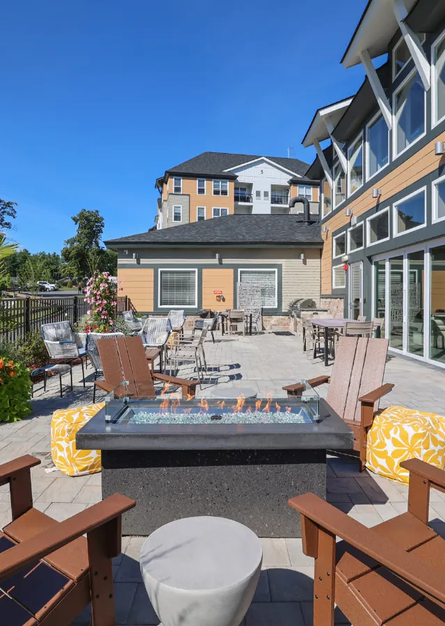 Charming outdoor patio with modern fire pit, surrounded by cozy seating, vibrant plants, and a stylish building backdrop.