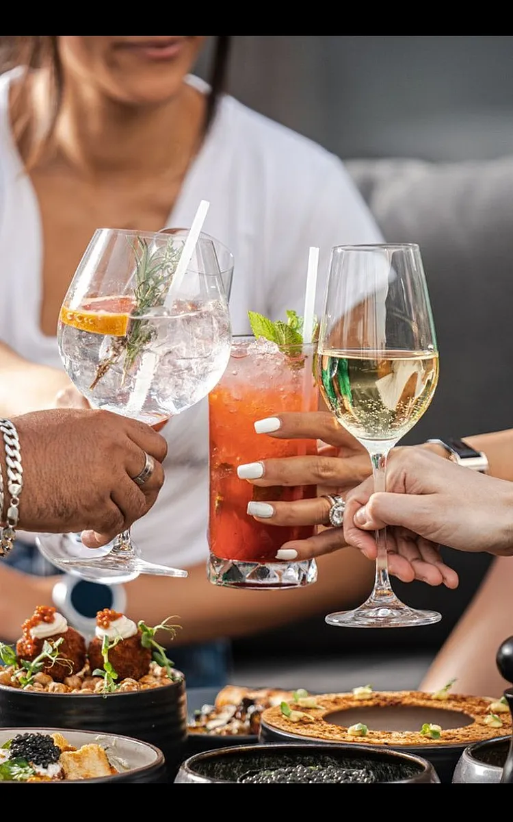 Vibrant social scene with friends toasting over gourmet appetizers, featuring colorful cocktails and sophisticated table setting.