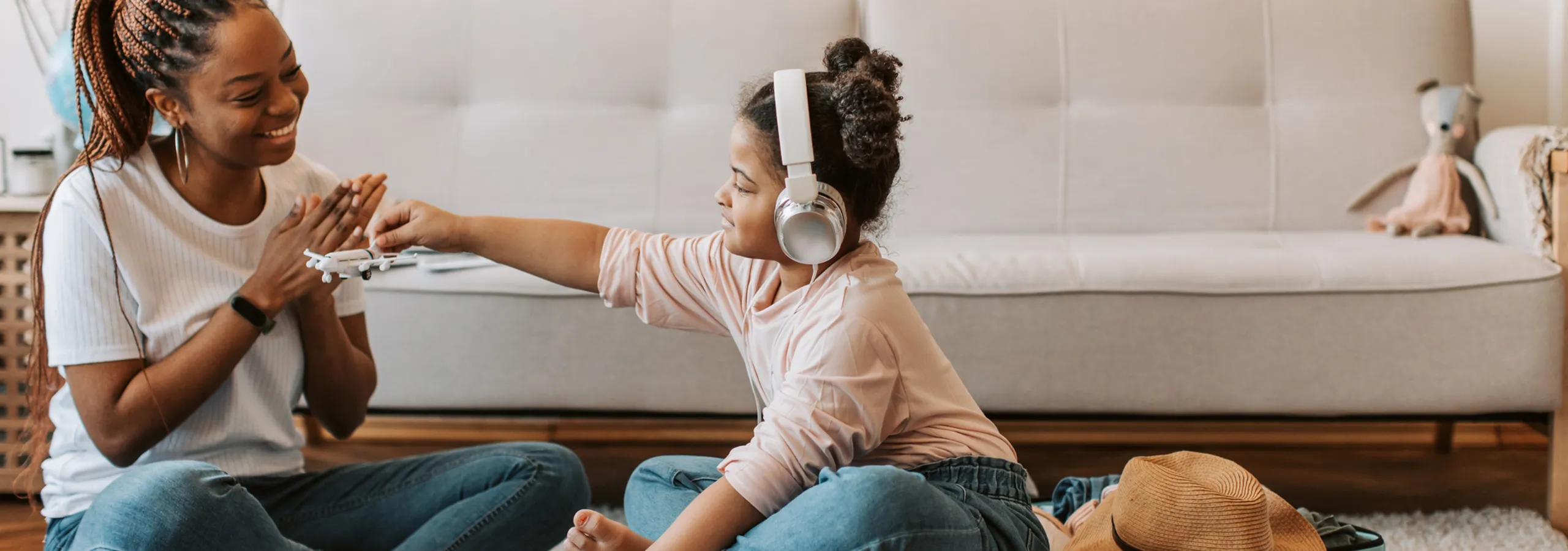 Cheerful living space with a cozy sofa, showcasing a joyful moment of play and bonding between a woman and a child wearing headphones.