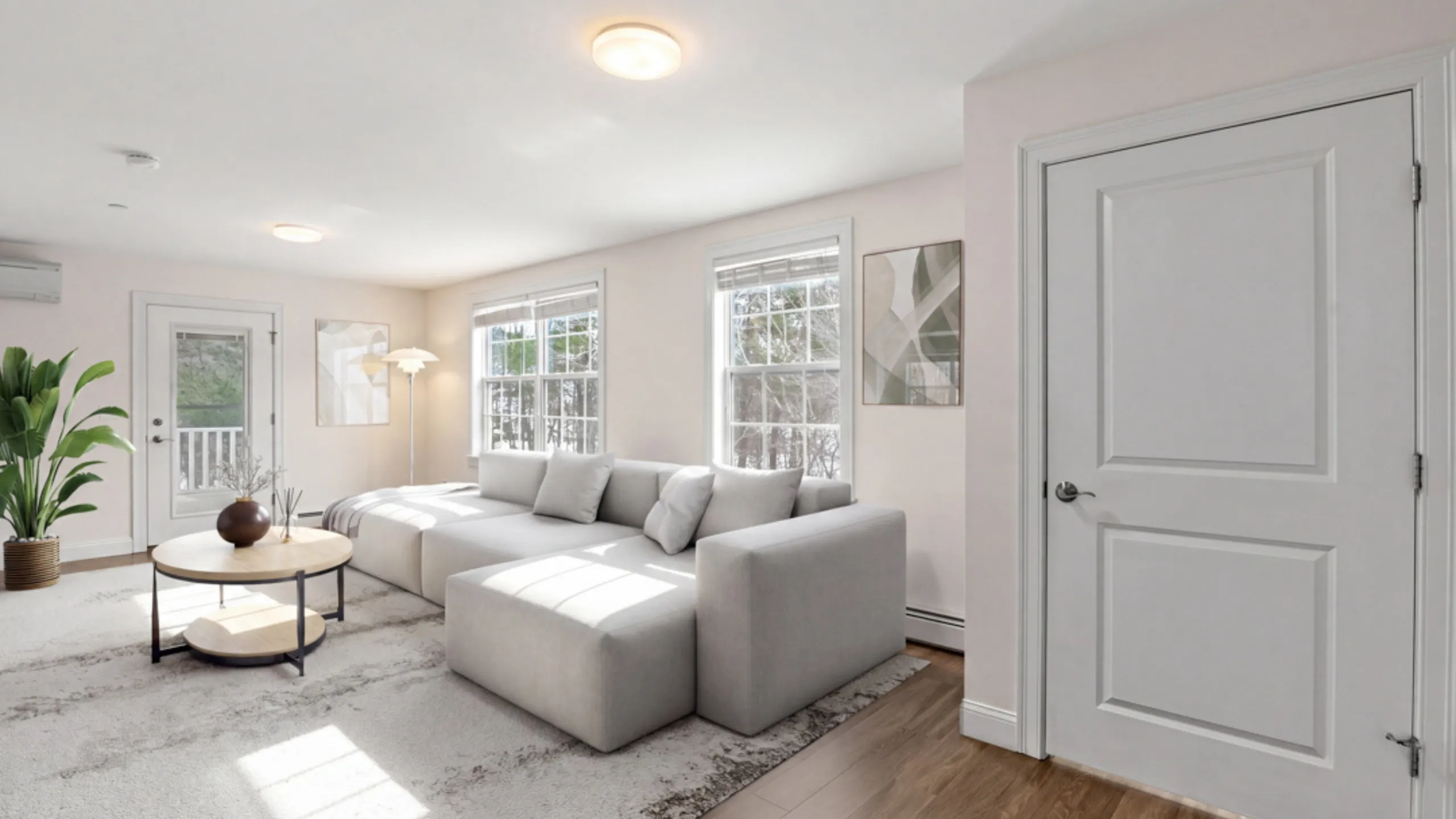 Bright and inviting living room featuring a stylish gray sofa, modern decor, and abundant natural light through large windows.