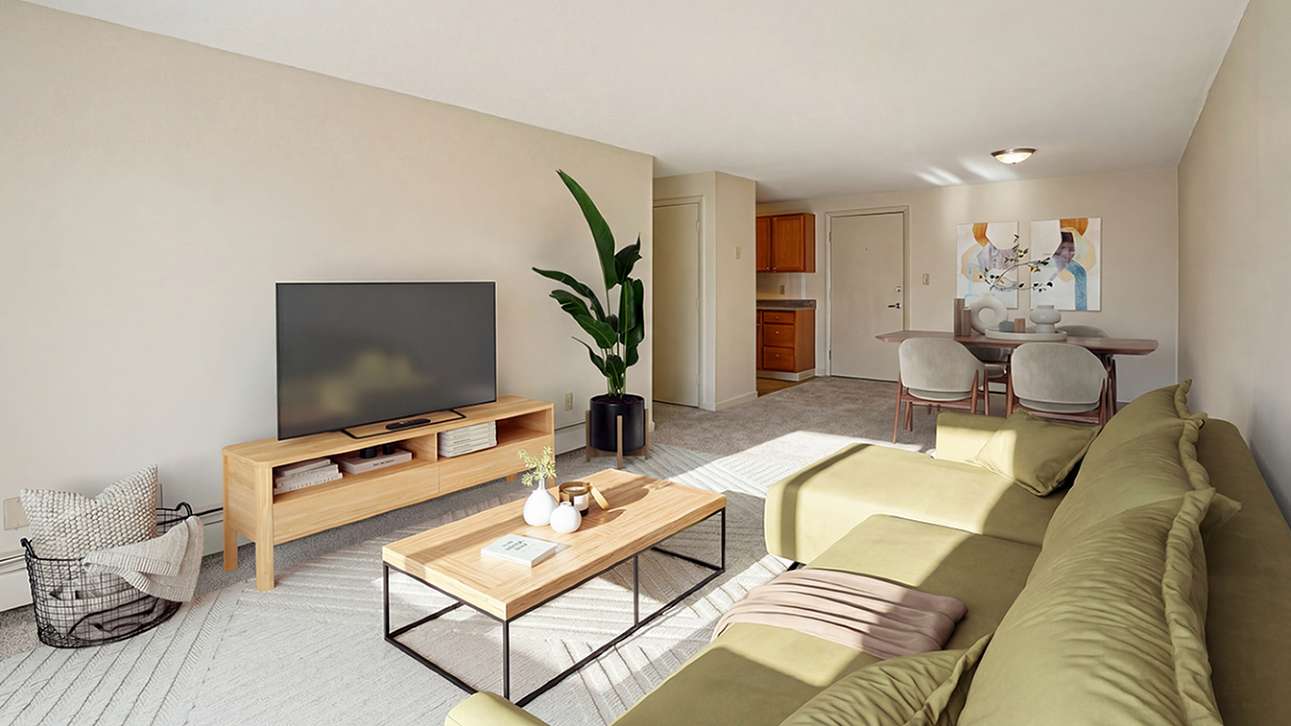 Bright and inviting living room with modern decor, featuring a large green sofa, sleek wooden coffee table, and entertainment center with a flat-screen TV. The space flows seamlessly into a cozy dining area and a compact kitchen.