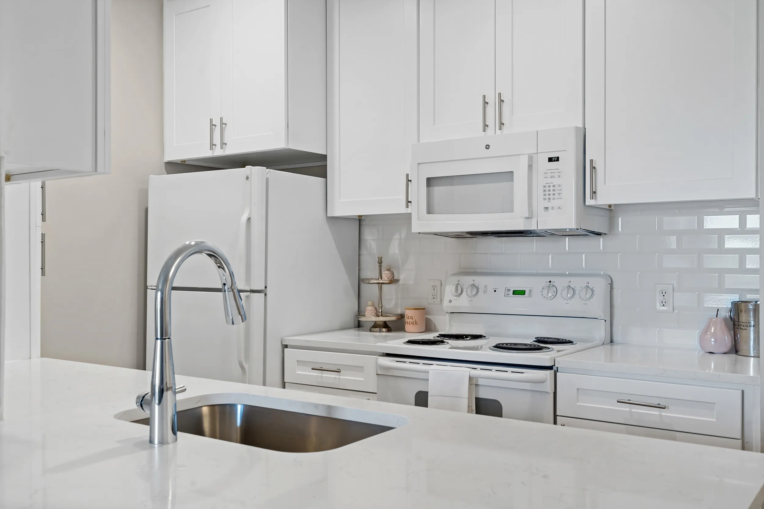 Modern kitchen with sleek white cabinetry, stainless steel appliances, and a stylish faucet, perfect for culinary adventures.