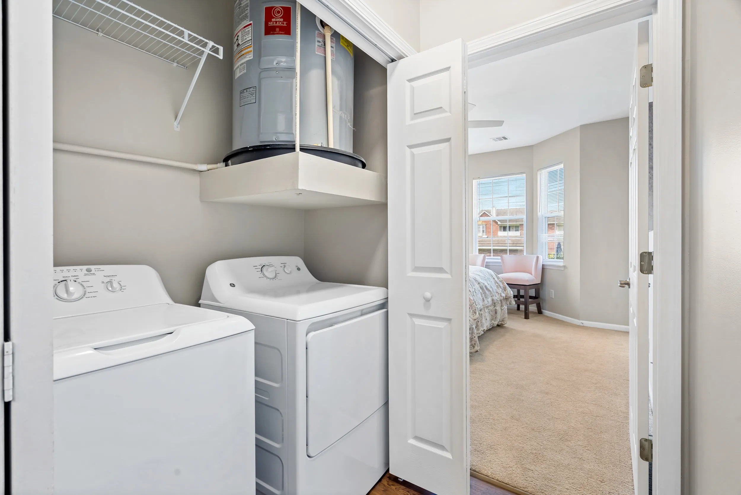 Modern in-unit laundry with sleek washer and dryer adjacent to a sunlit bedroom, offering convenience and comfort.