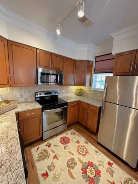 Charming modern kitchen with stainless steel appliances, elegant wood cabinetry, and a cozy floral rug for a warm touch.