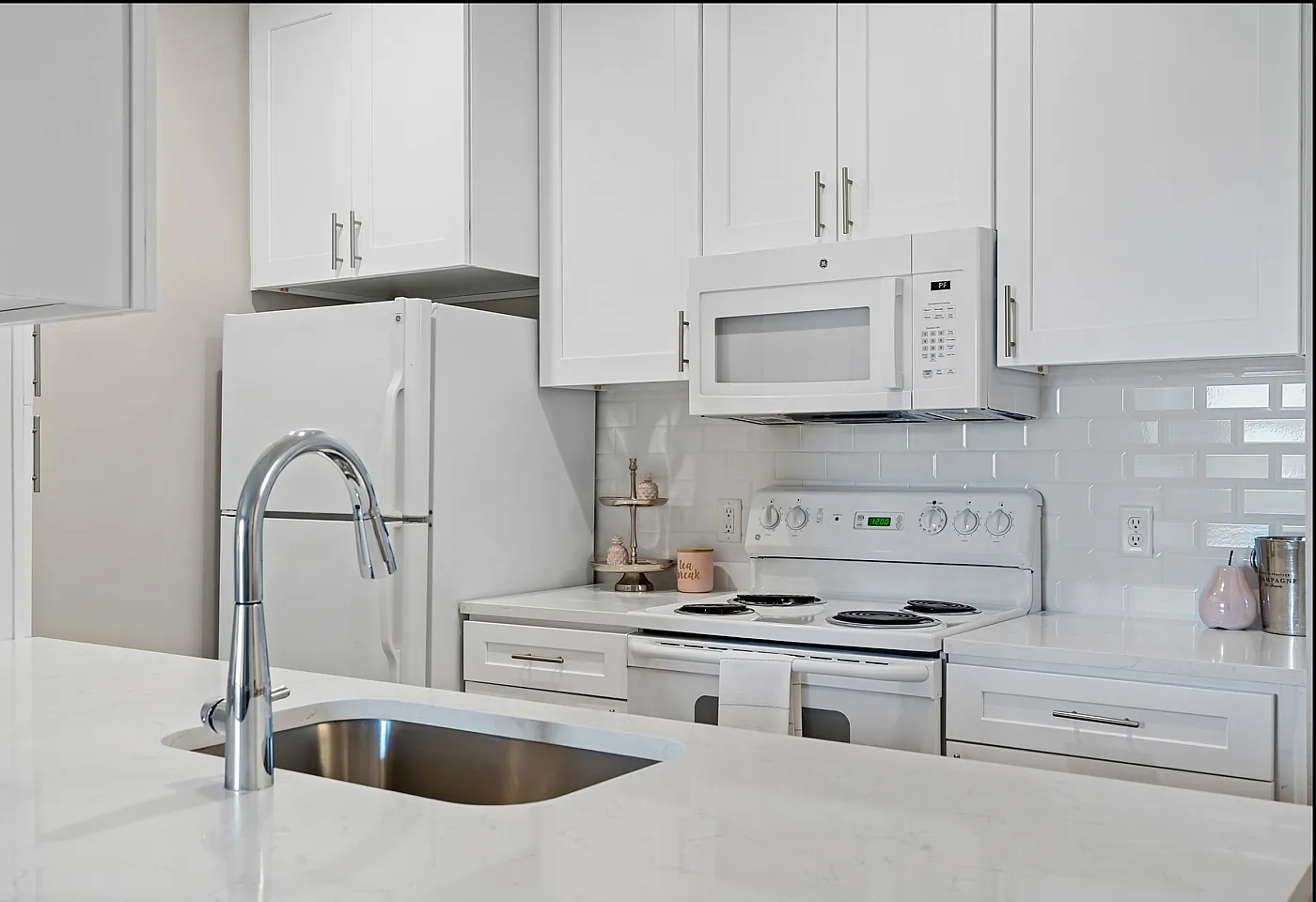 Sleek modern kitchen featuring pristine white cabinetry, a built-in microwave, and a polished chrome faucet.