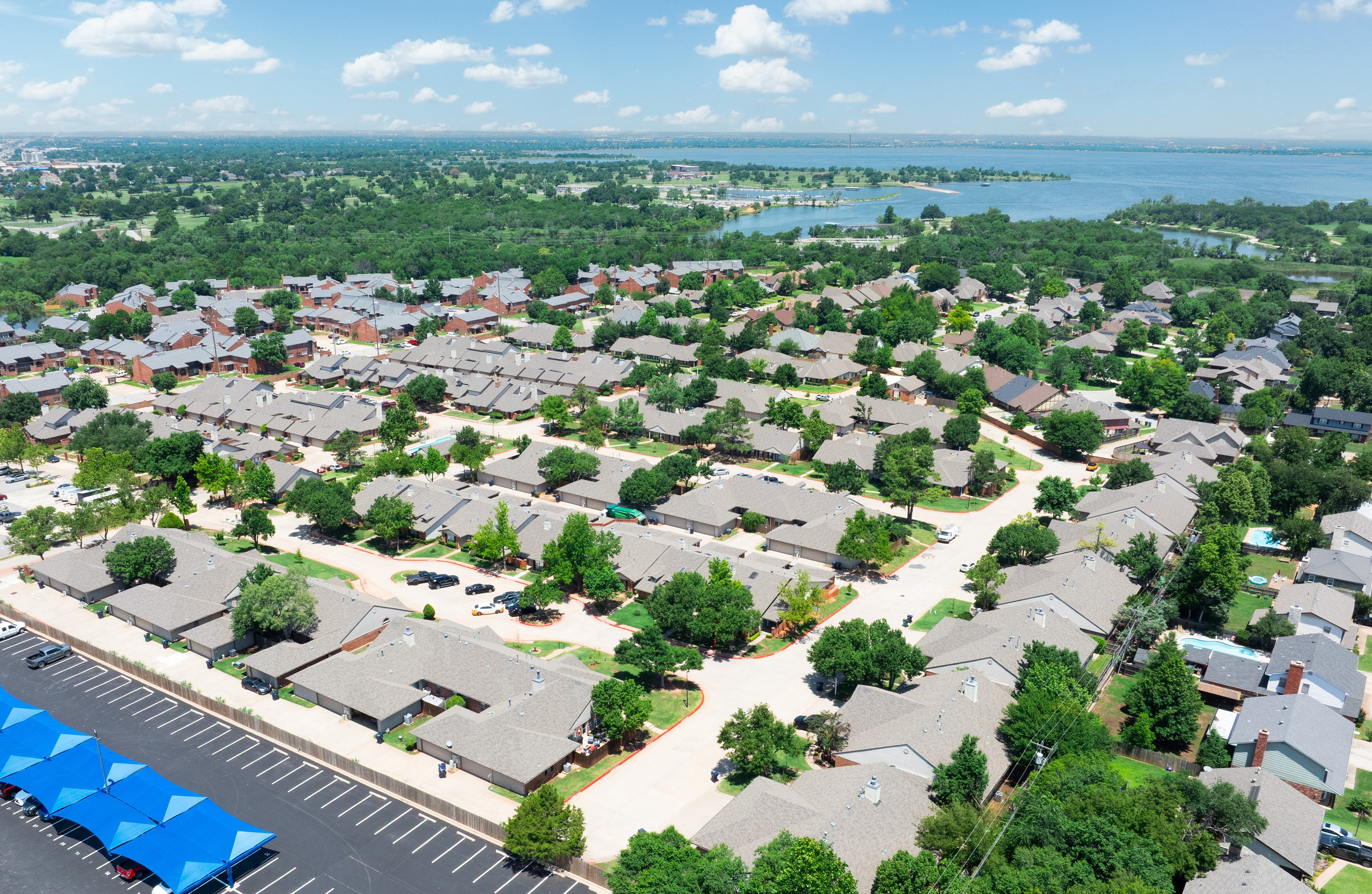 Aerial view of a charming suburban neighborhood with neatly arranged houses, lush greenery, and serene waterfront in the background.