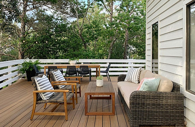 Stylish outdoor patio featuring comfy wicker furniture, wooden deck, and vibrant greenery.