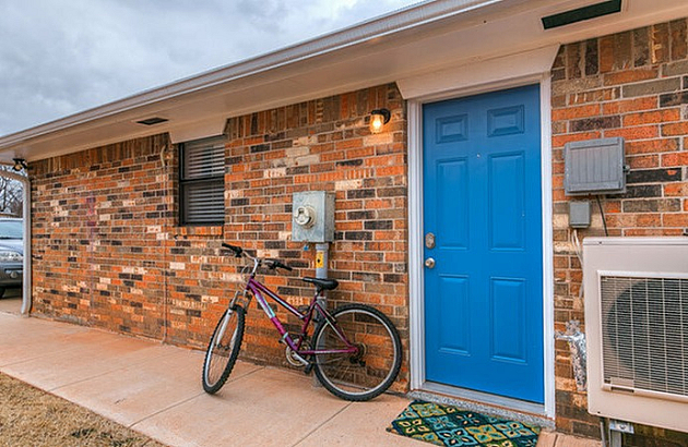 Inviting exterior of a brick home with a vibrant blue door and bicycle on the sidewalk.