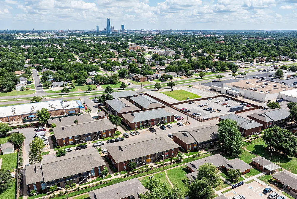 Vibrant aerial view of a well-planned apartment complex surrounded by lush greenery and urban amenities in a bustling cityscape.