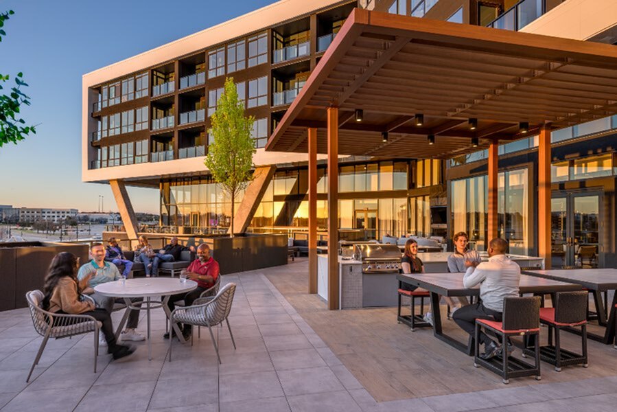 Modern terrace at sunset featuring elegant outdoor seating, dining areas, and a sleek barbecue under a stylish pergola, perfect for social gatherings.