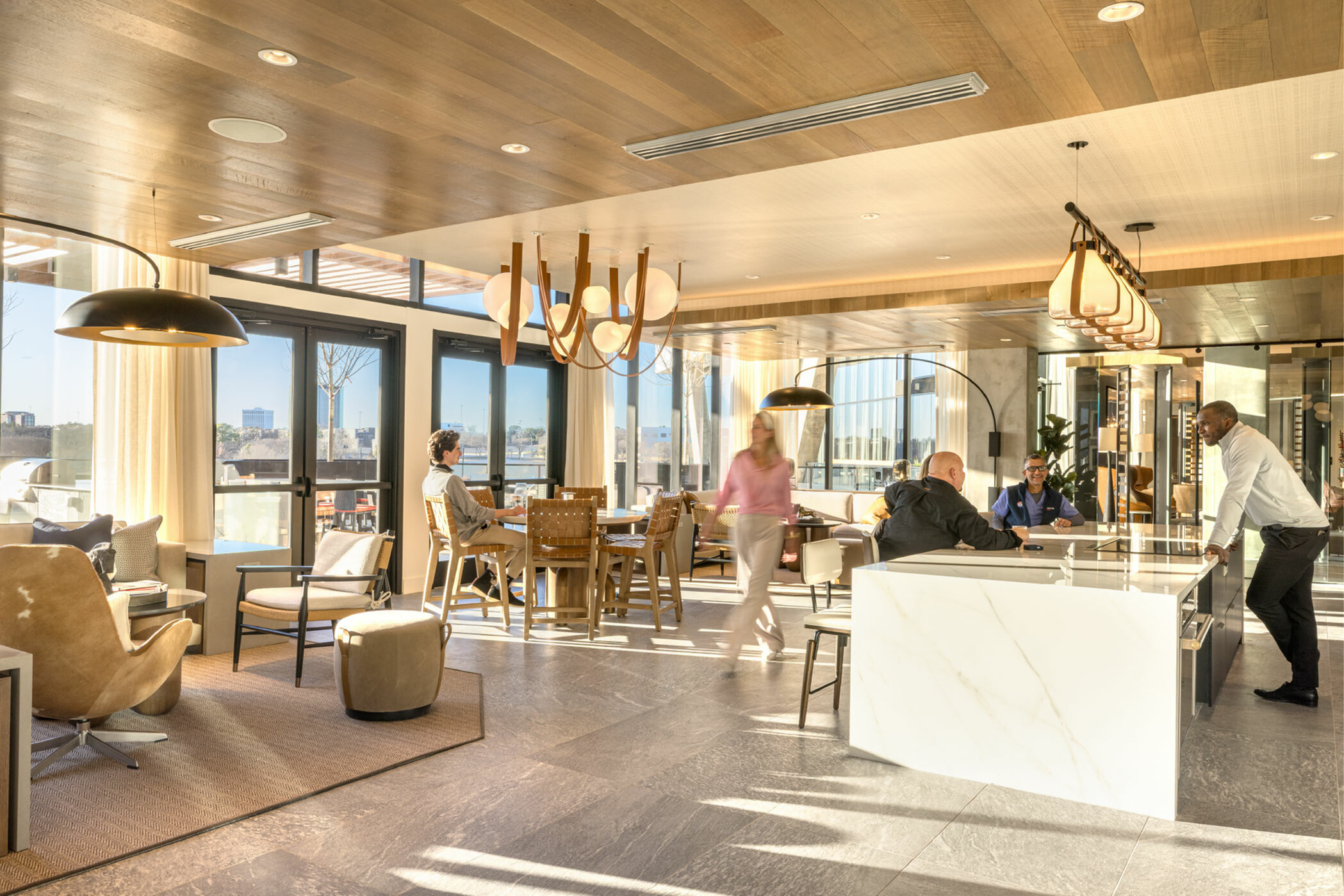 Modern communal living space with stylish decor, featuring a spacious kitchen, elegant lighting, and floor-to-ceiling windows offering stunning city views.