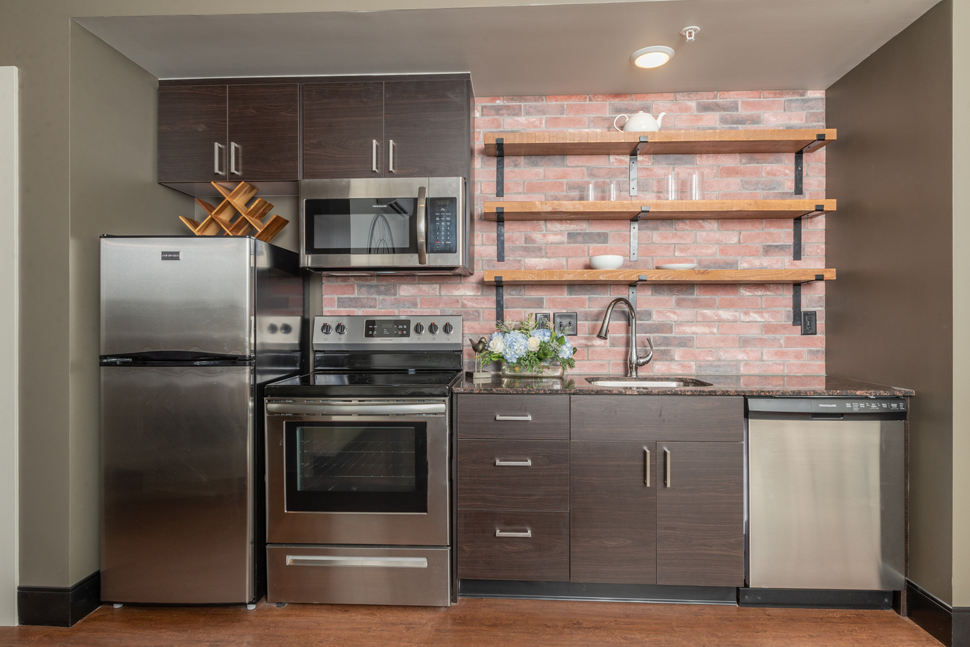 apartment in studio apartment with gray cabinets and exposed brick wall