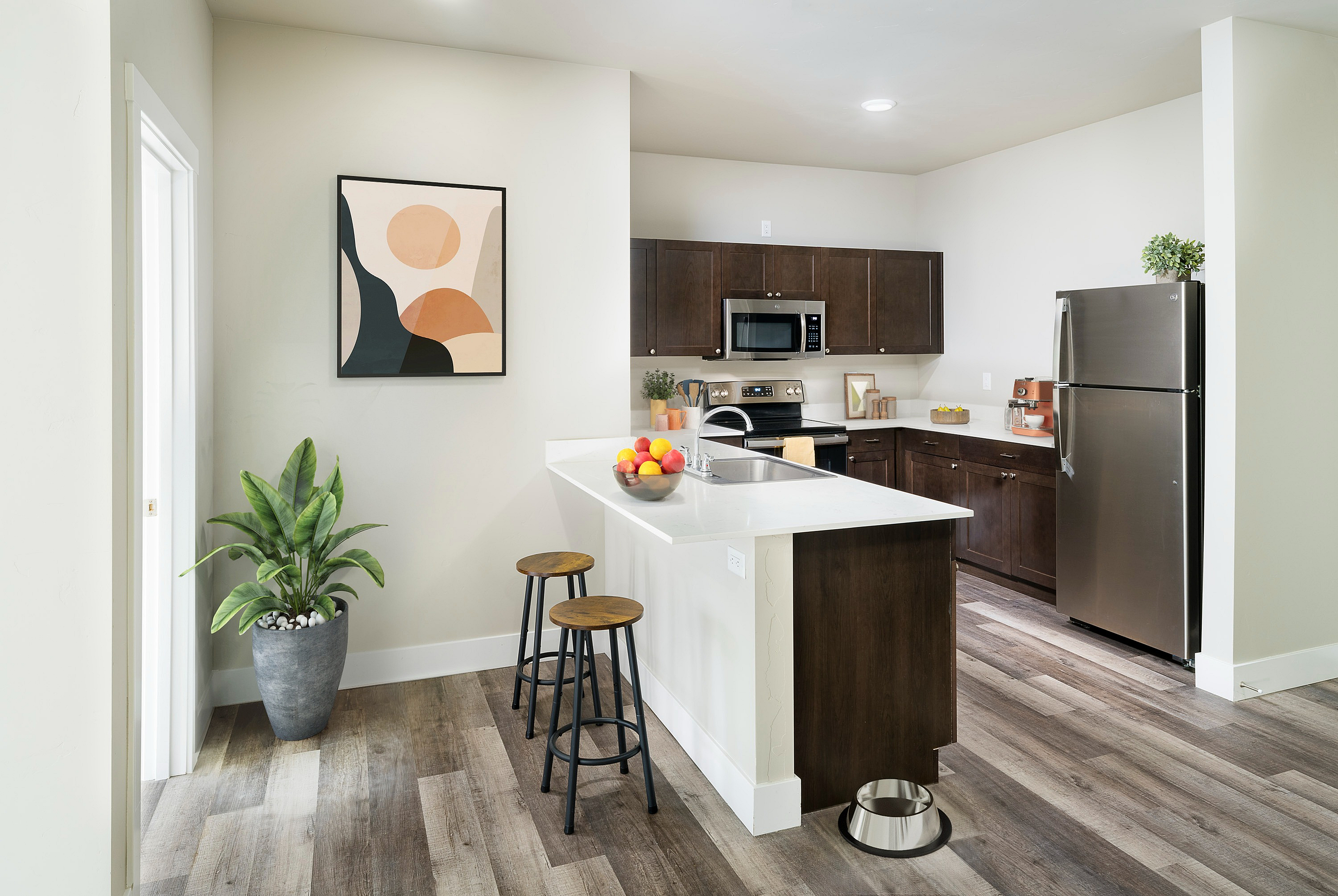 Sleek kitchen with dark cabinets, stainless steel appliances, and an island with bar stools.