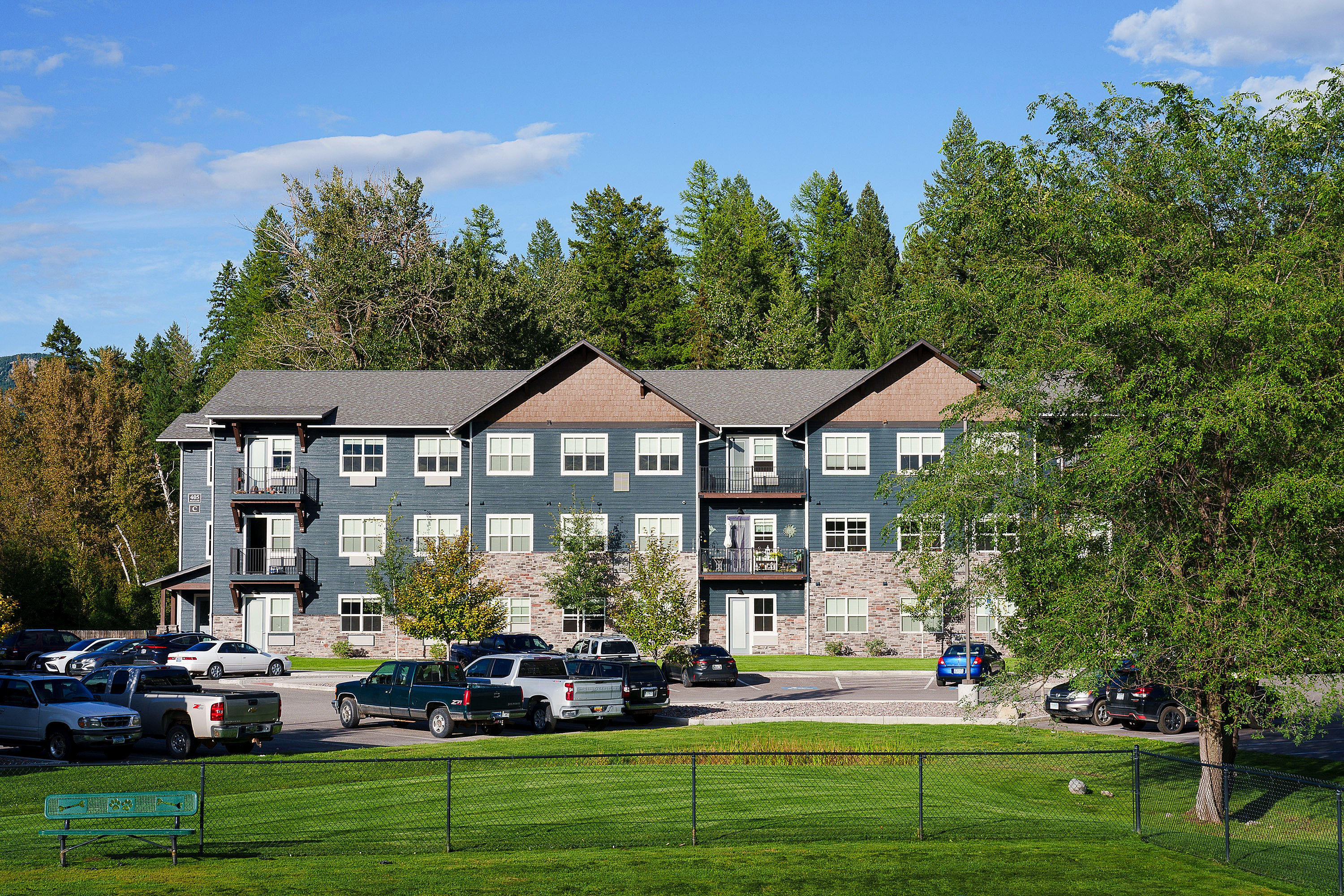 Scenic view of a modern three-story apartment building surrounded by lush greenery.