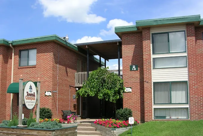 Inviting brick apartment complex with charming greenery and vibrant flower displays at the entrance.