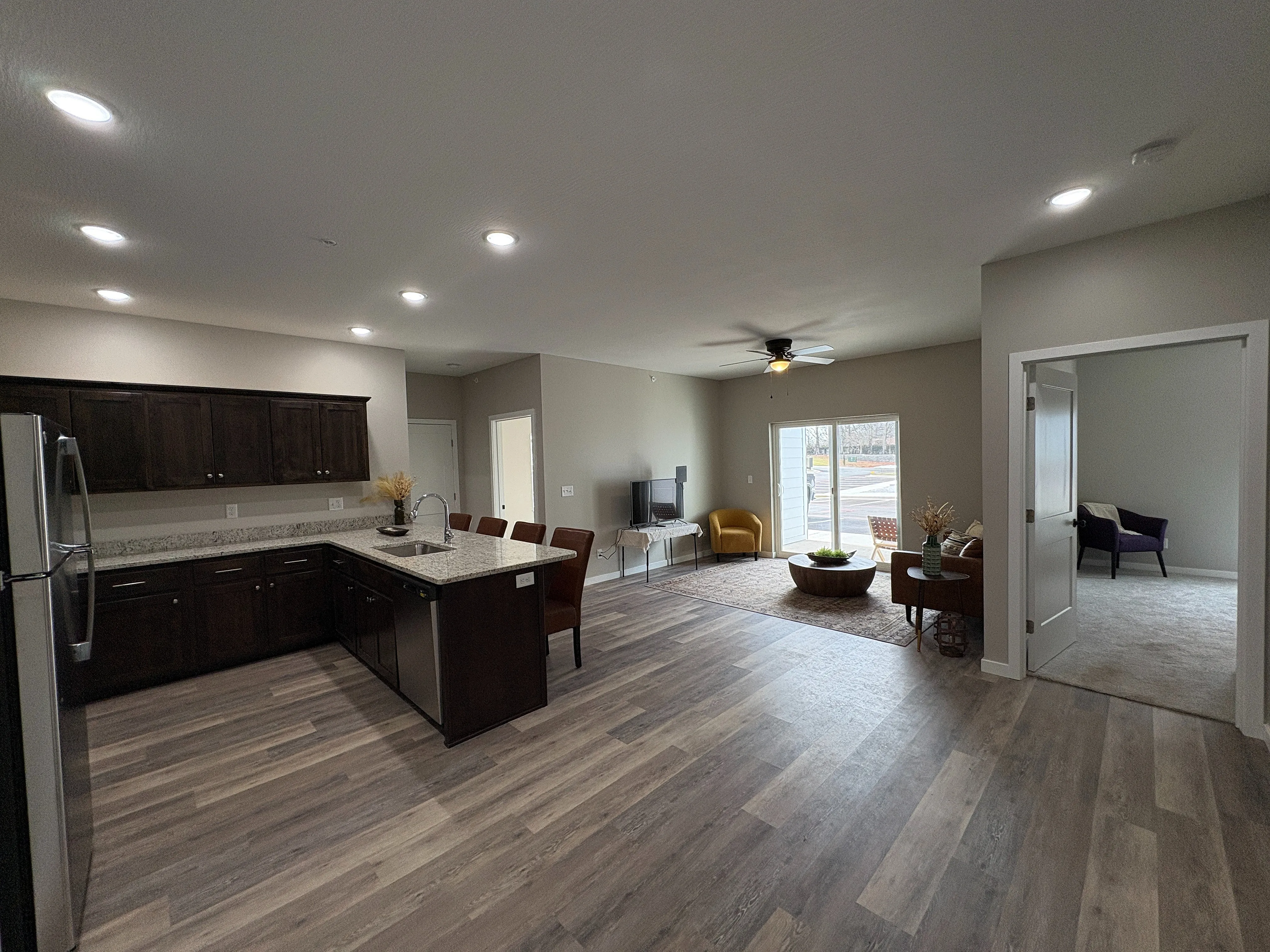 Modern open-concept living space with a sleek kitchen, wooden flooring, and bright natural light, ideal for entertaining.