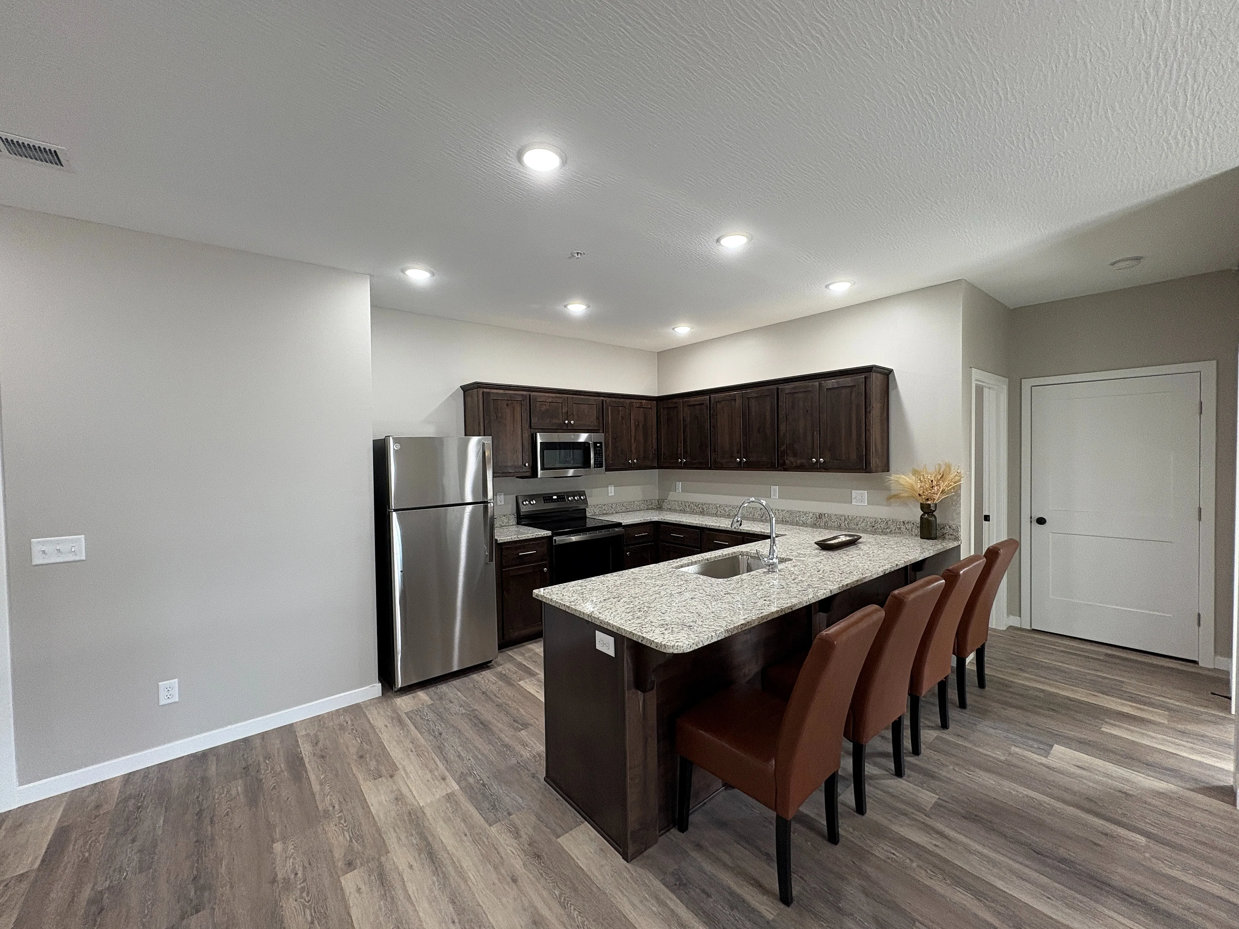 Modern kitchen with elegant granite countertops, stainless steel appliances, and cozy seating area with plush chairs.
