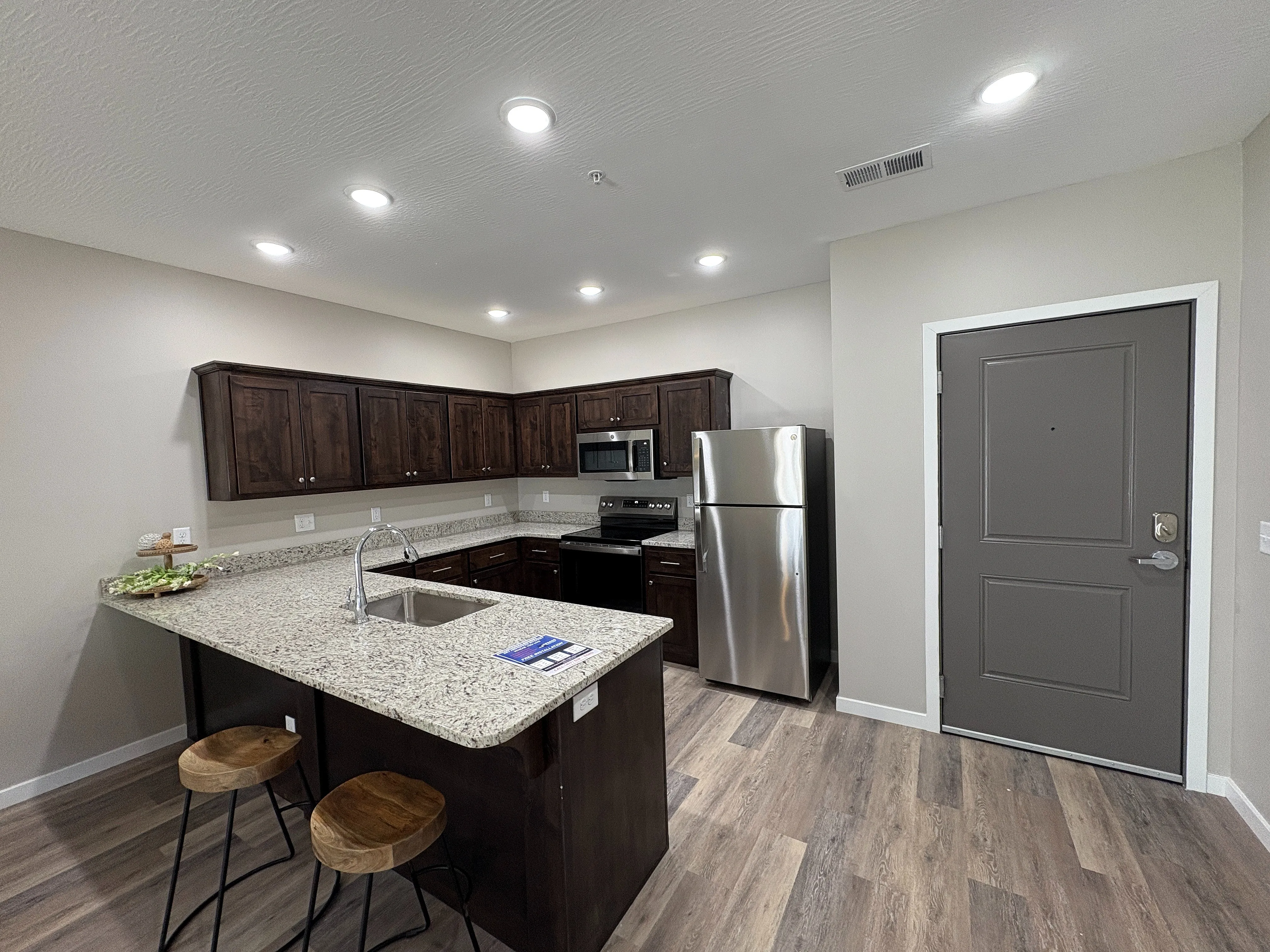 Modern kitchen with sleek granite countertops, stainless steel appliances, and warm wooden cabinetry, perfect for culinary creations.