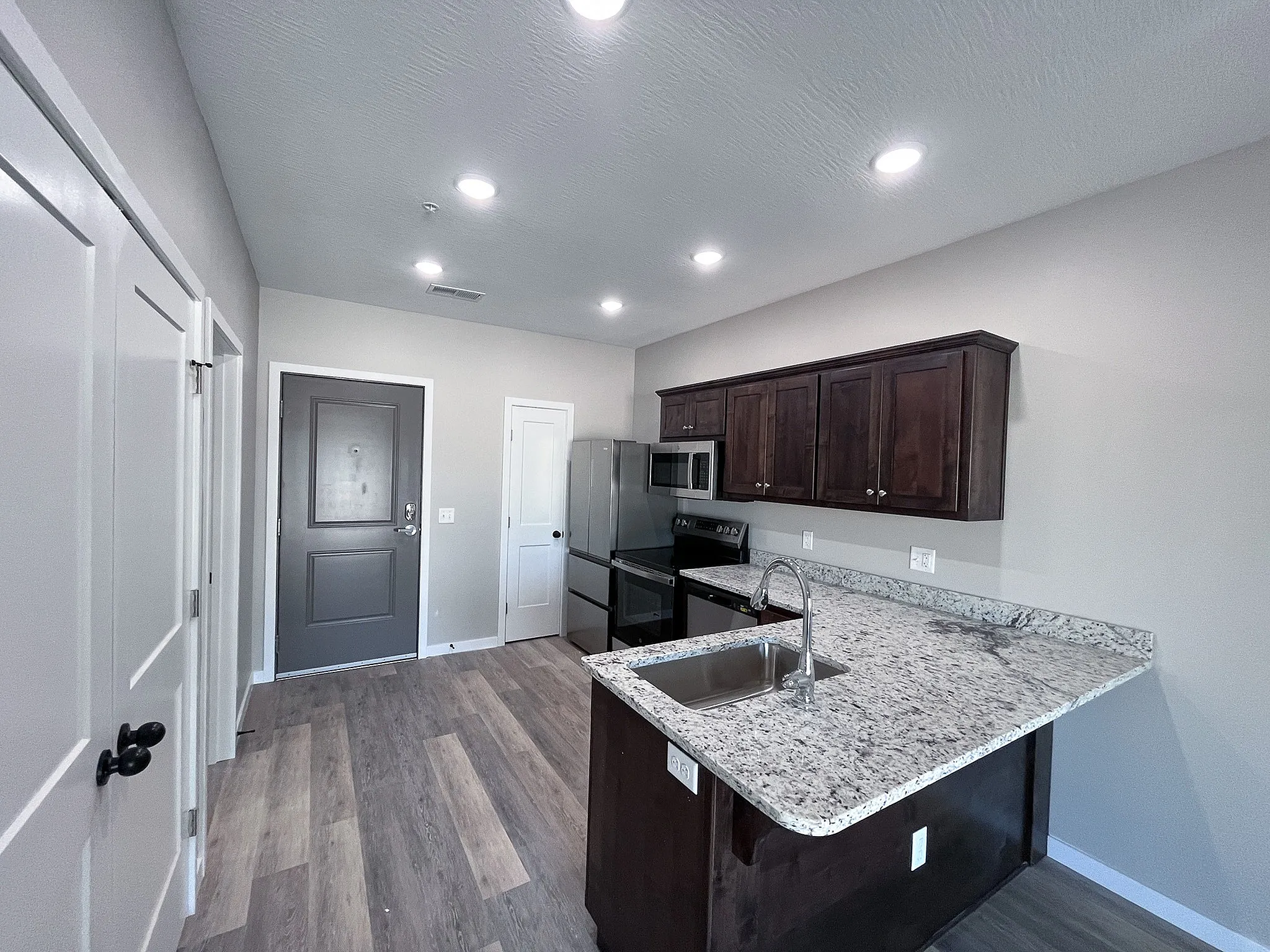 Inviting modern kitchen with sleek granite countertops, dark wood cabinetry, and elegant recessed lighting.