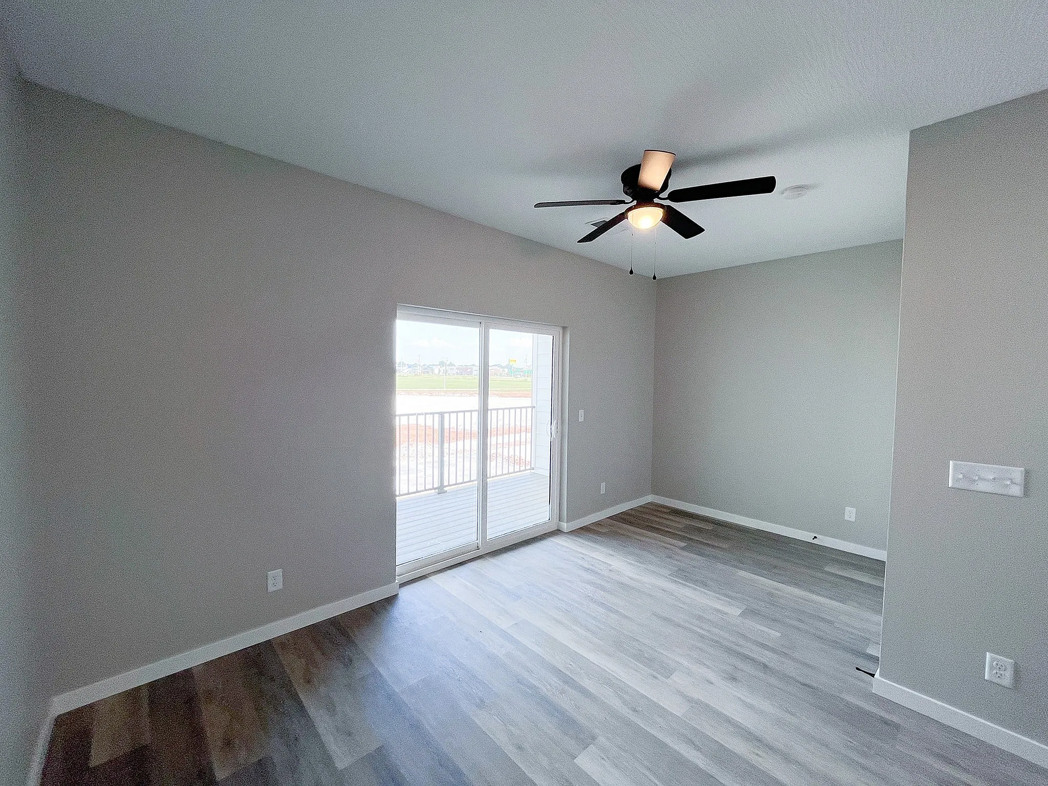 Bright and welcoming living space with modern ceiling fan and sliding glass doors opening to a serene view, perfect for relaxation or entertaining.