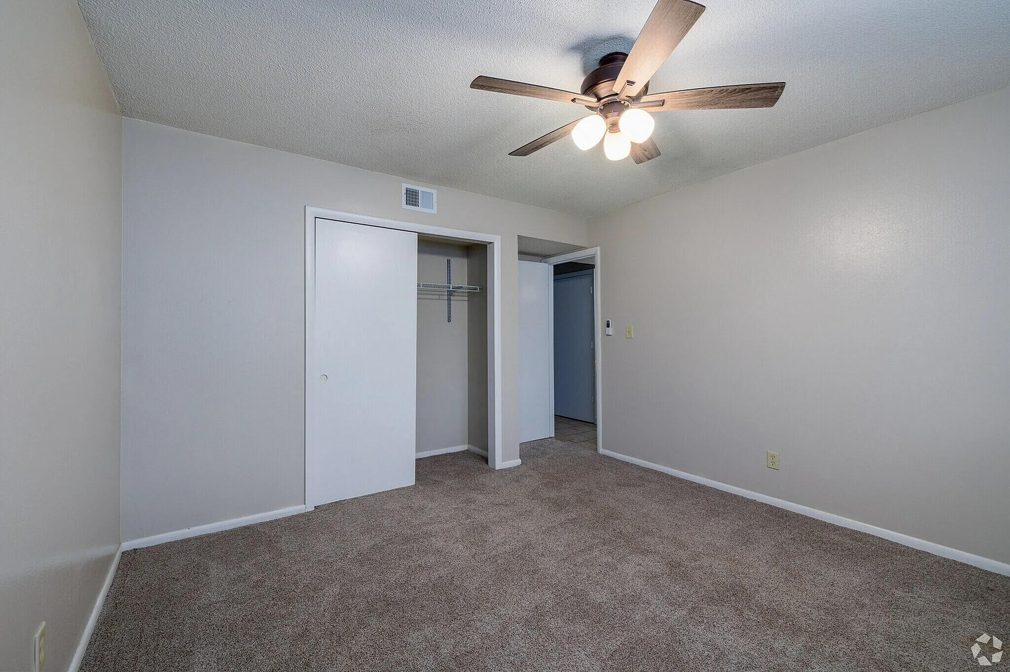 Inviting bedroom with plush carpet, ceiling fan, and ample closet space.