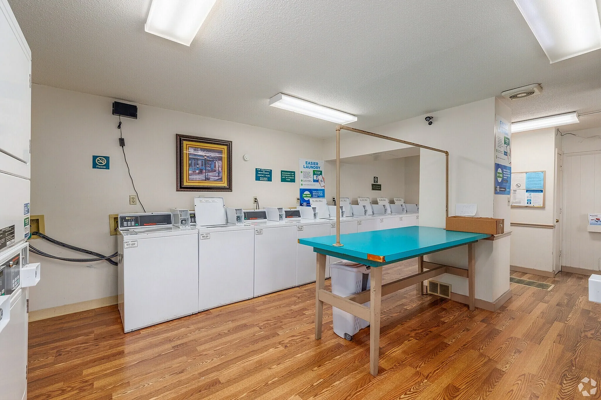 Inviting communal laundry room with modern washers, hardwood floors, and a convenient folding station.