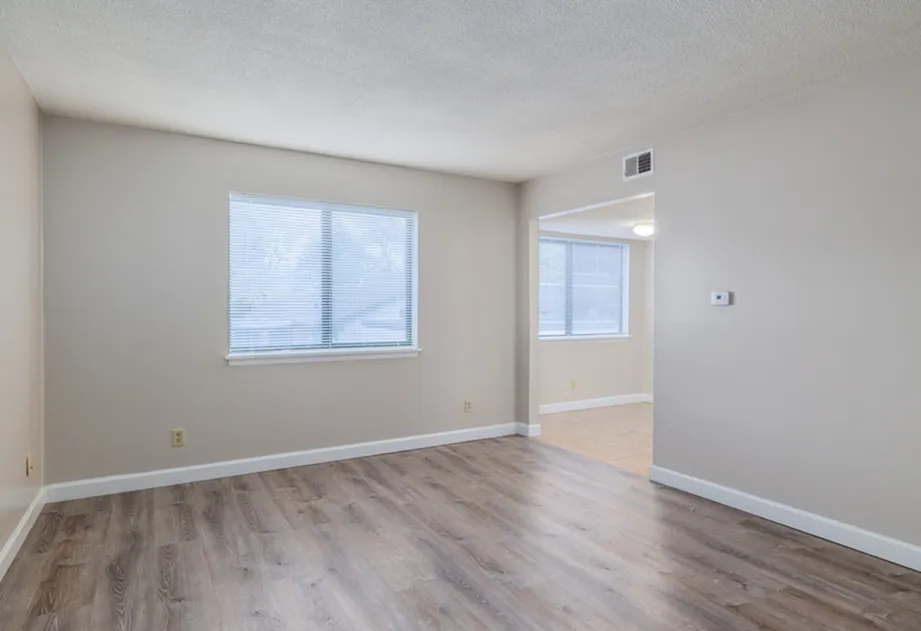 Bright and inviting living area with large window, modern wood flooring, and neutral wall tones.