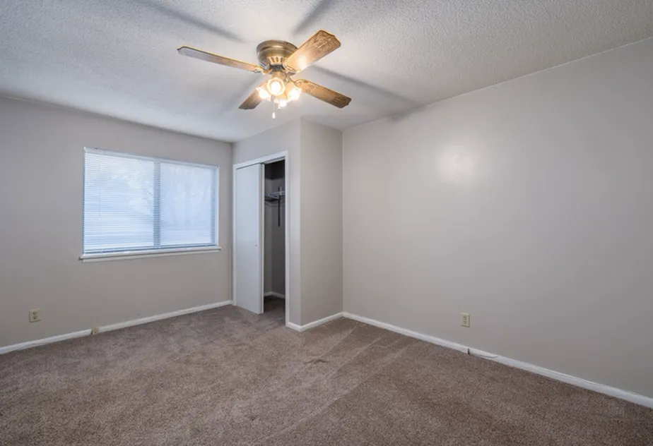 Inviting bedroom with cozy carpet, large window, and a convenient ceiling fan, creating a serene atmosphere.