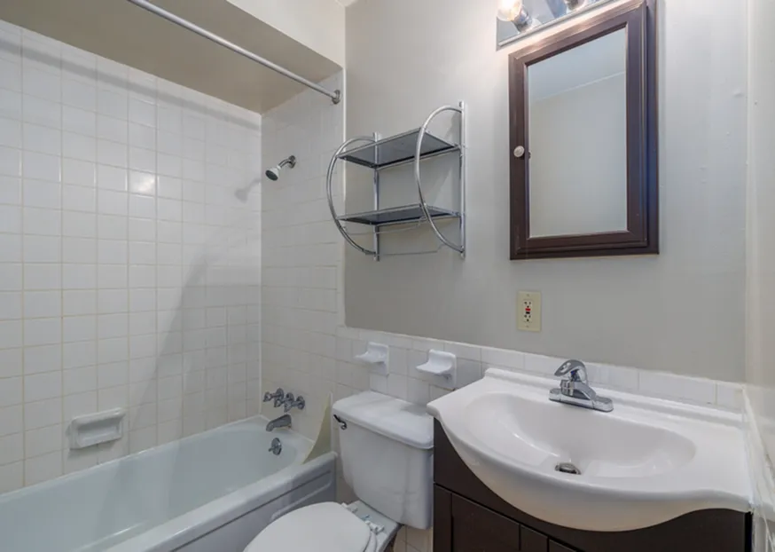 Bright and modern bathroom featuring sleek vanity, tiled walls, and inviting bathtub.