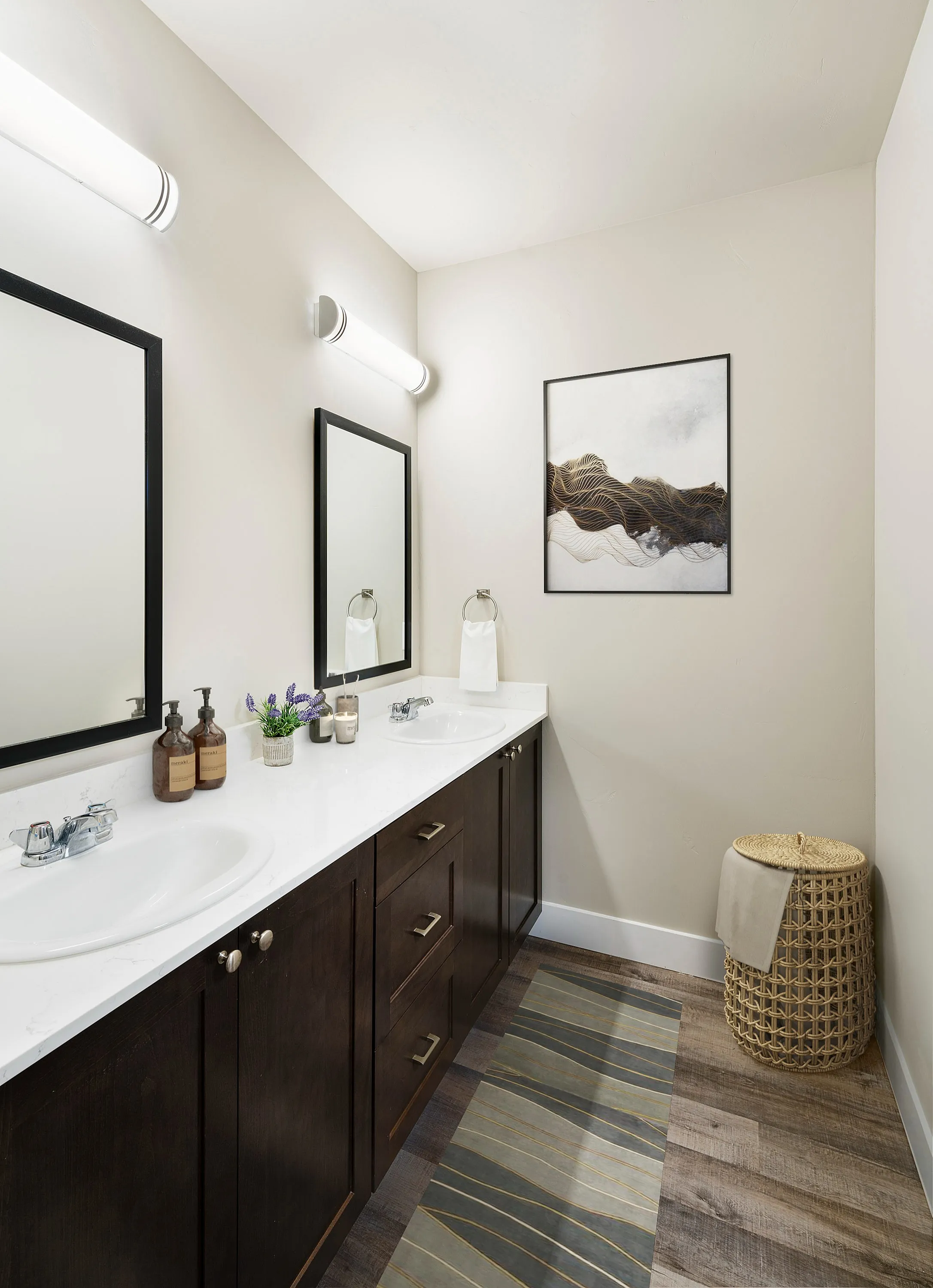 Exquisite bathroom with dual sinks, elegant dark wood cabinetry, and modern decor, showcasing contemporary art and ambient lighting.