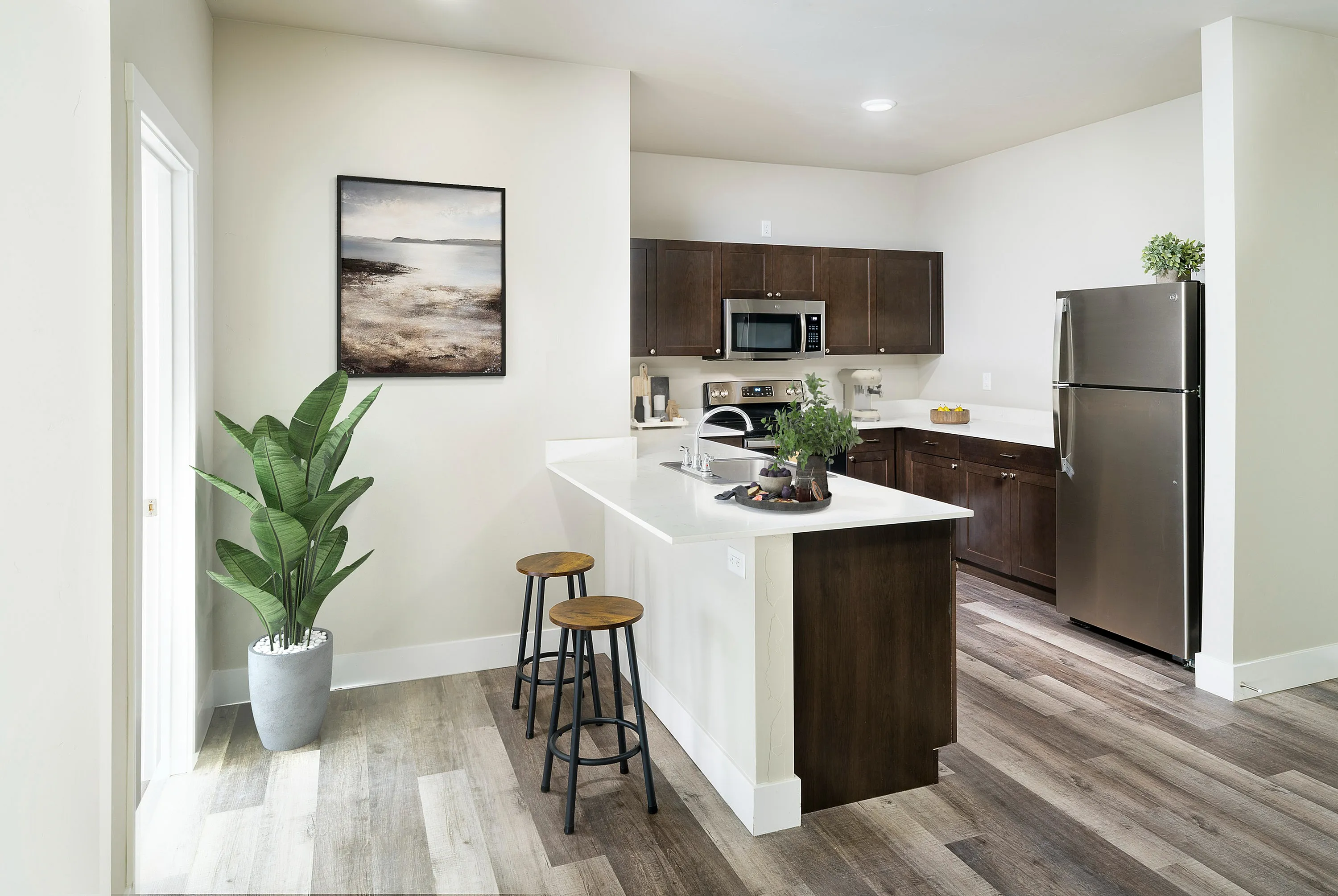 Modern kitchen with sleek cabinetry, stainless steel appliances, and an inviting breakfast bar accented by stylish stools and vibrant greenery.