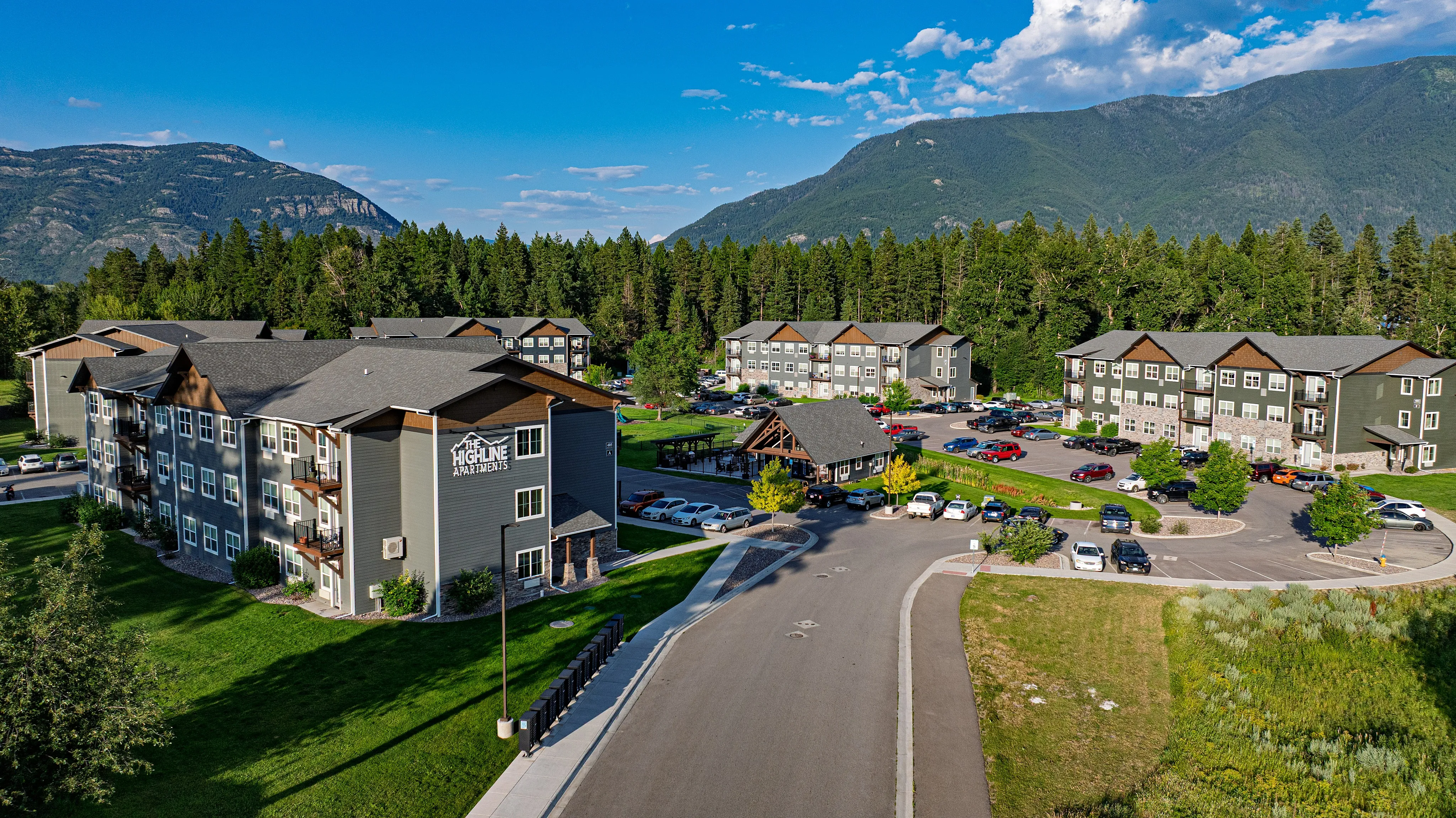 Charming apartment complex nestled amidst lush greenery with scenic mountain views, offering abundant parking and modern living in a serene environment.