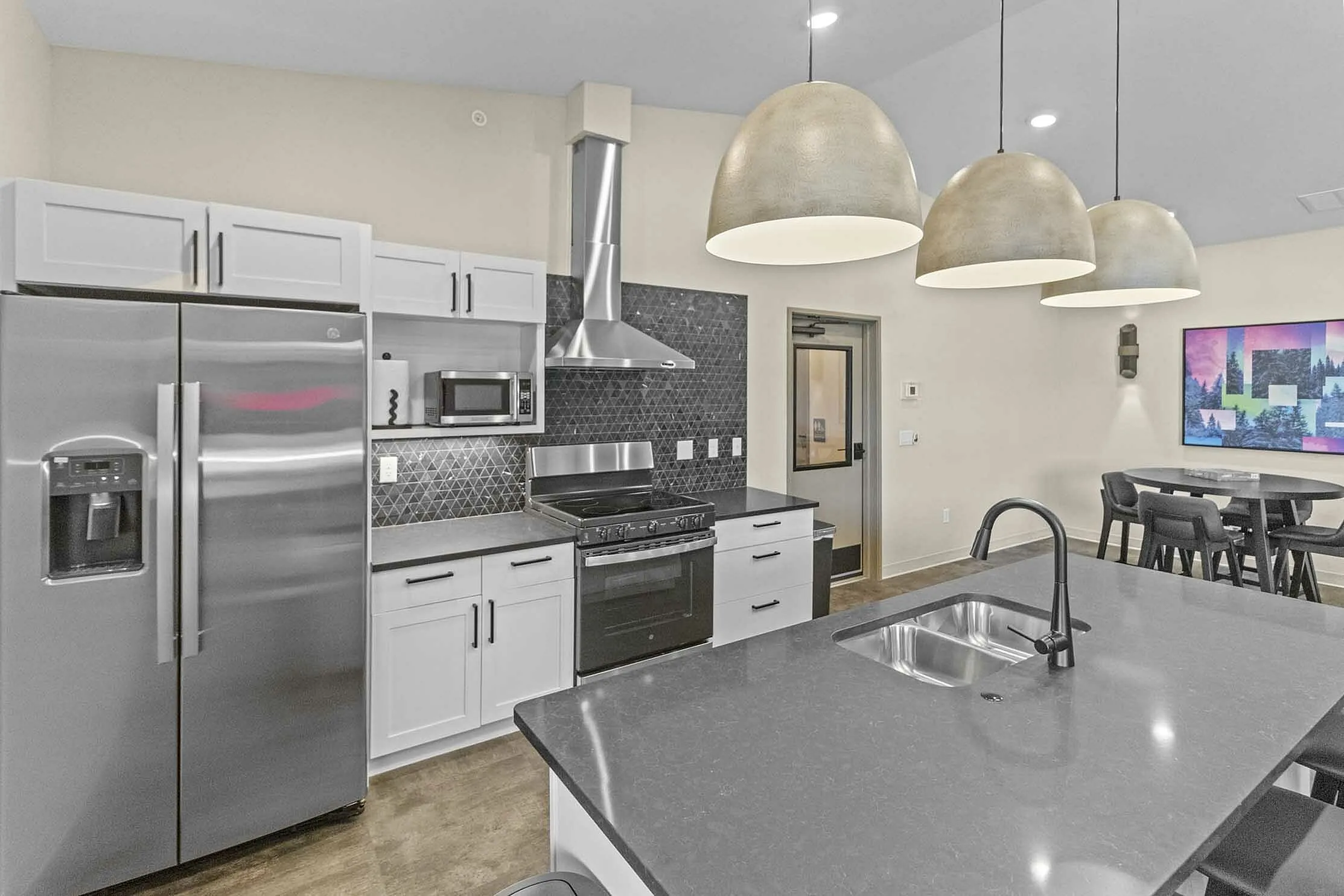 Modern kitchen with sleek stainless steel appliances, elegant pendant lighting, and a spacious island counter.