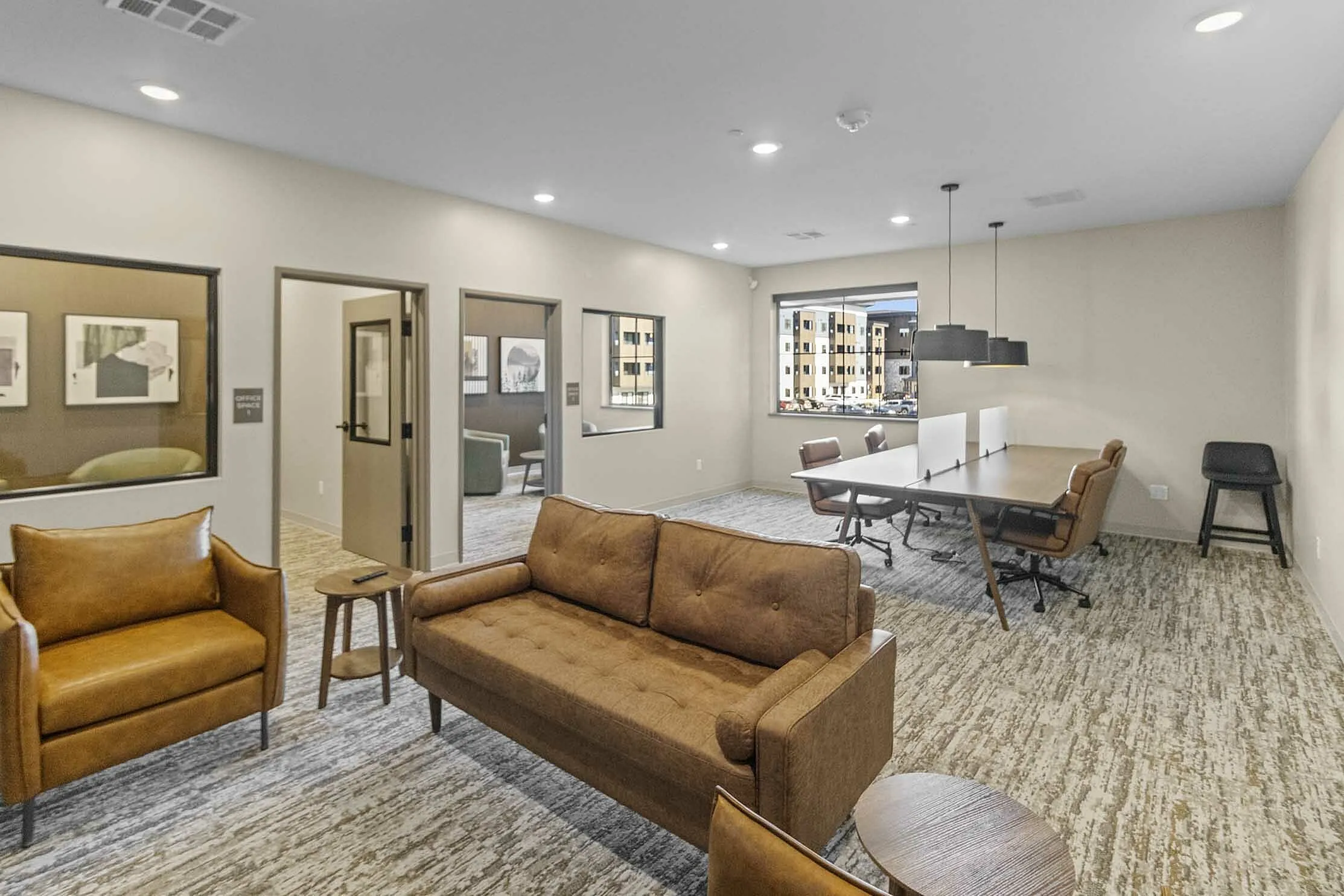 Modern office space featuring cozy leather seating, a conference table with stylish chairs, and large windows providing ample natural light.