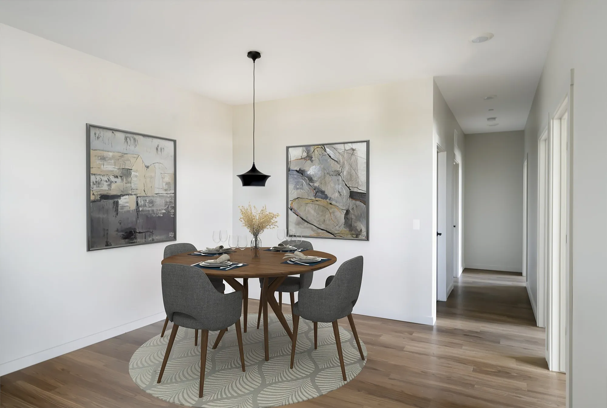 Modern dining area with elegant wooden table, stylish gray chairs, contemporary artwork, and a sleek pendant light, creating an inviting atmosphere.