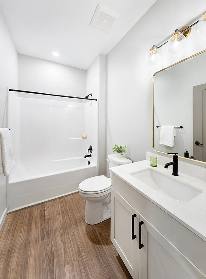 Bright and modern bathroom featuring elegant lighting, sleek vanity, and stylish wood flooring.