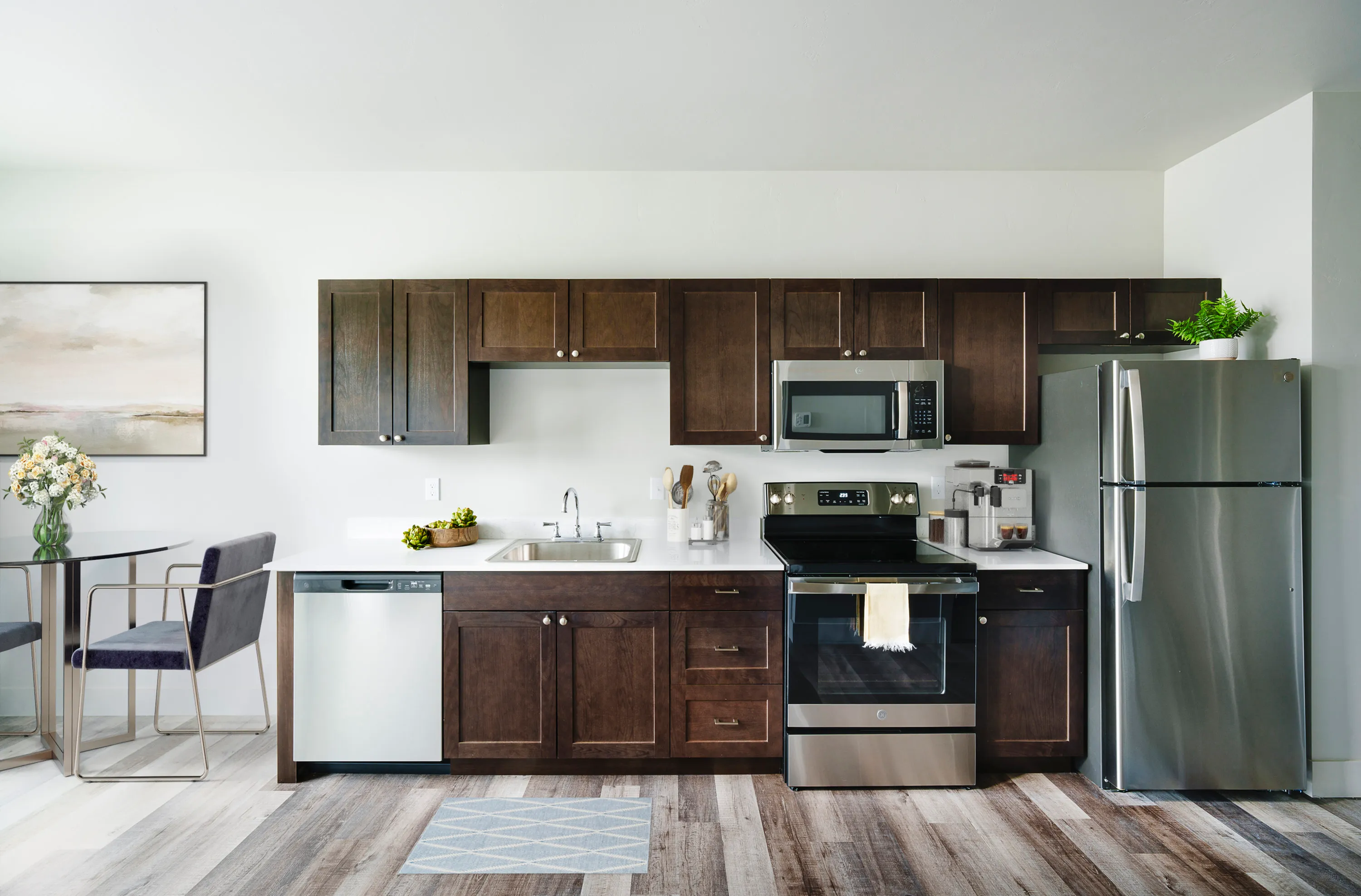 Modern kitchen with sleek stainless steel appliances, dark wood cabinets, and a cozy dining area with contemporary decor.