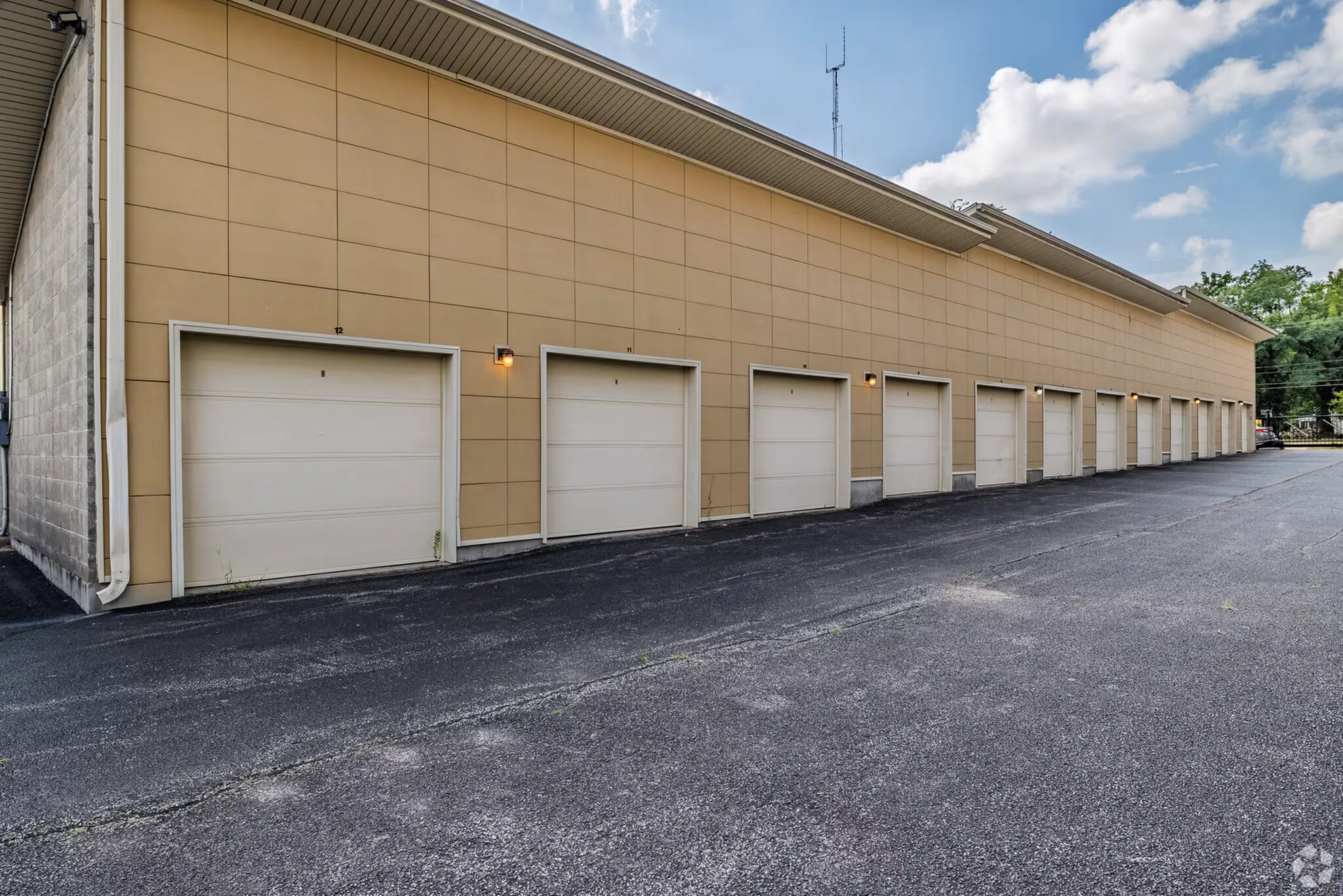 Modern apartment complex garage featuring multiple secured parking spaces, sleek beige paneling, and convenient outdoor lighting.