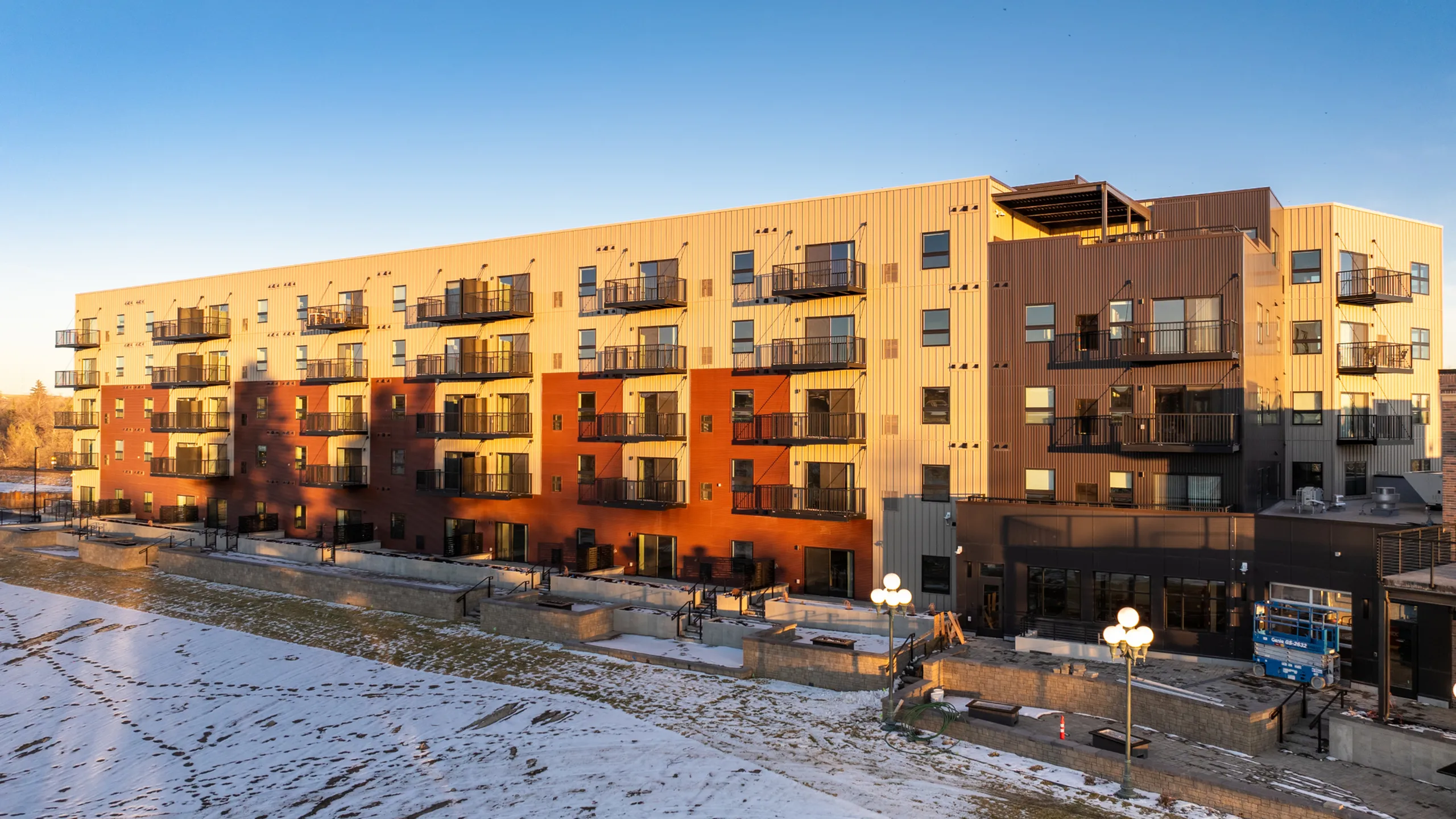Contemporary apartment building with multiple balconies and modern architectural design in a winter setting.