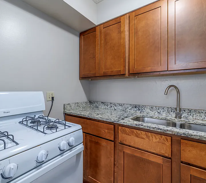 Cozy kitchen with elegant wooden cabinetry, sleek granite countertop, and modern gas stove.